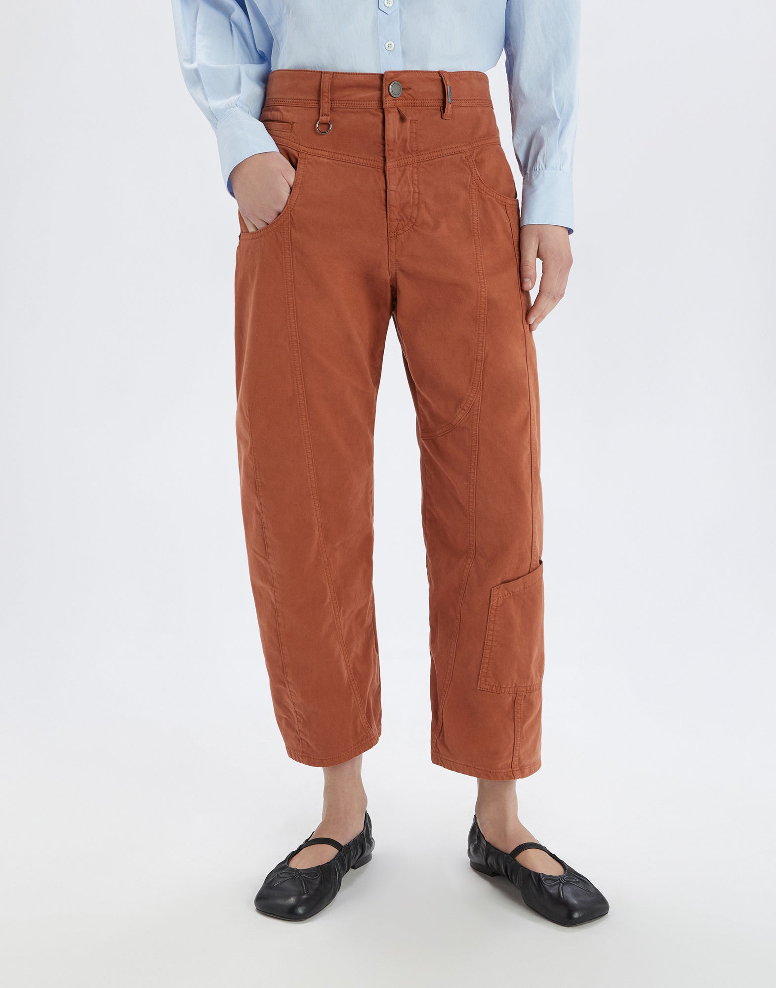 Frontalansicht der FURORE Hose in rostbrauner Farbe, getragen von einer Person. Die Hose zeigt sichtbare Nähte, aufgesetzte Taschen und Bootcut-Passform.