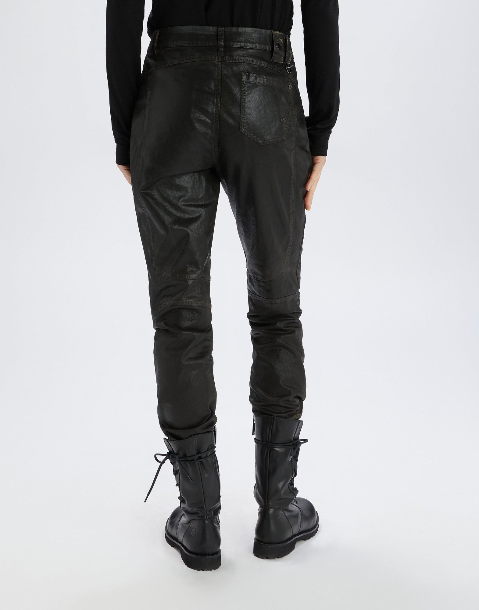 Back view of INKLING jeans with leather look, worn by a person with black boots and black top. Visible: back patch pockets, structured knee area, belt loops.