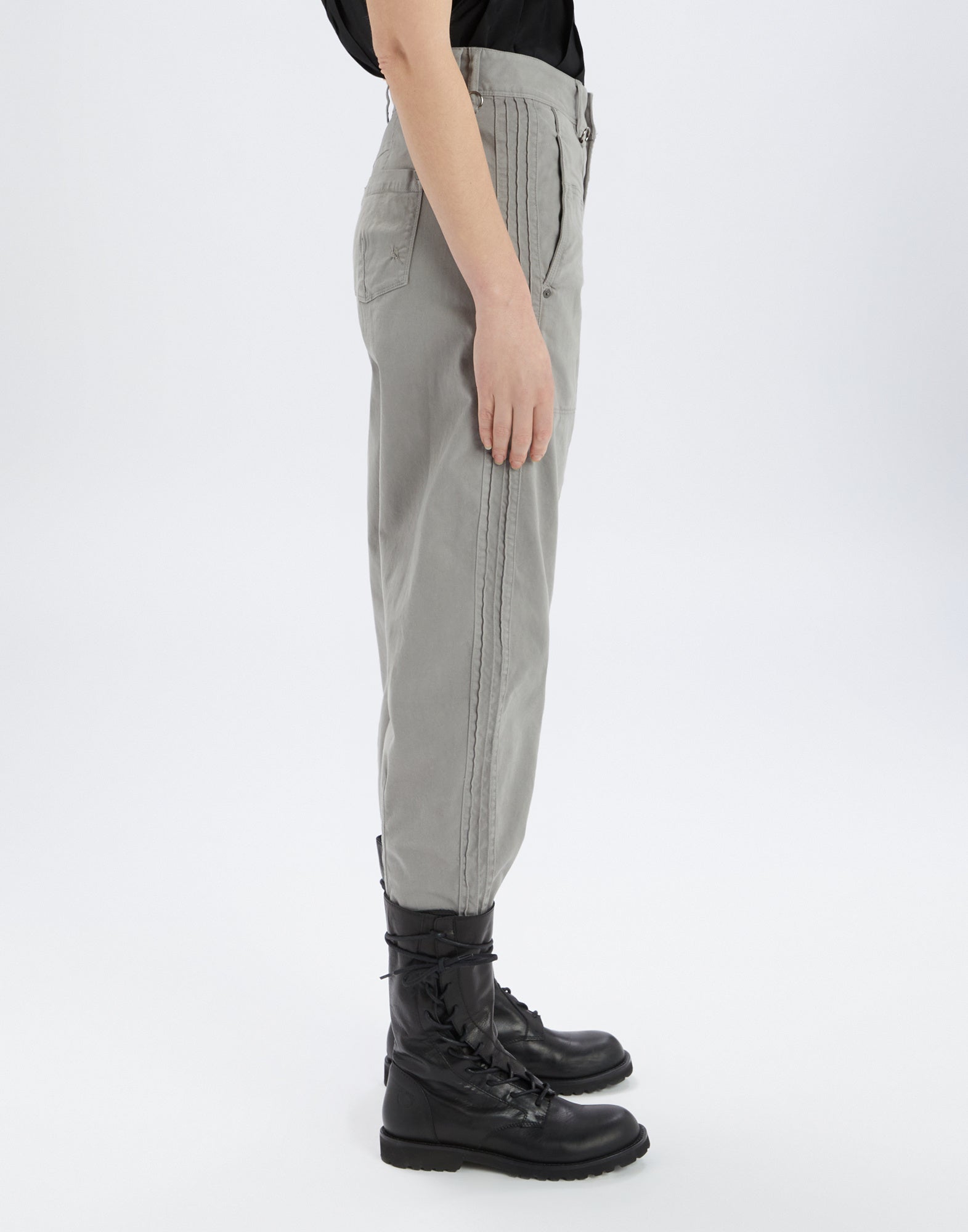 Side view of ACTIVATE pants in light grey with visible seams, side pockets, and belt loops, worn with black boots, modern workwear look.
