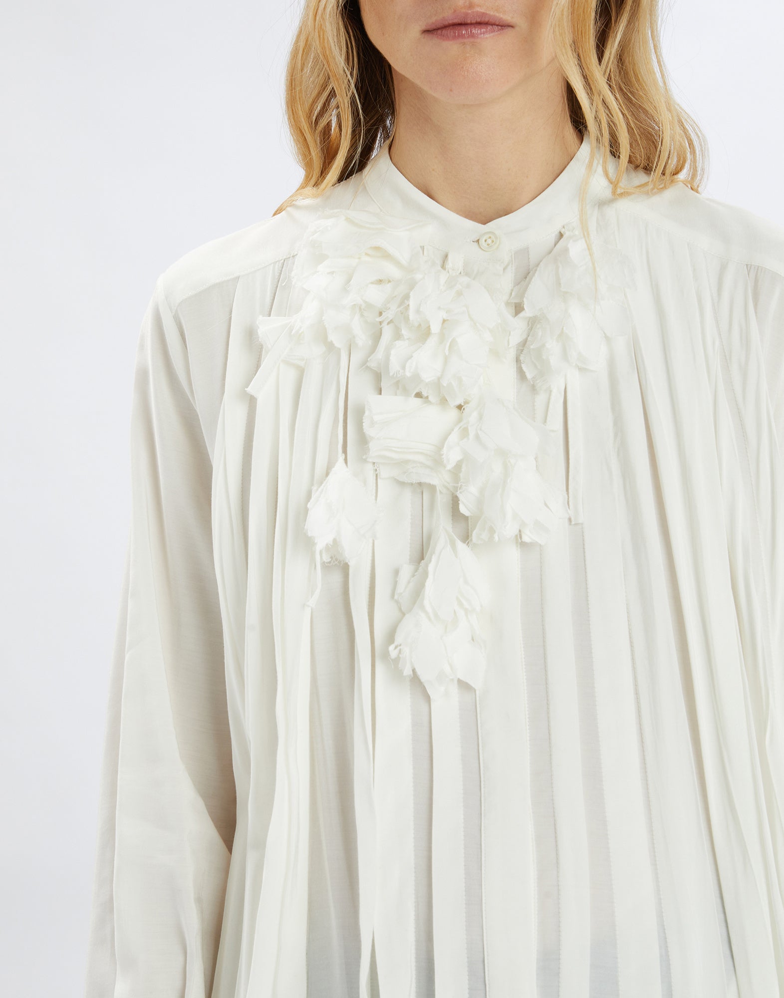 Close-up view of the GALAXY dress in white fabric with stand-up collar and removable floral applique decoratively placed at the front.