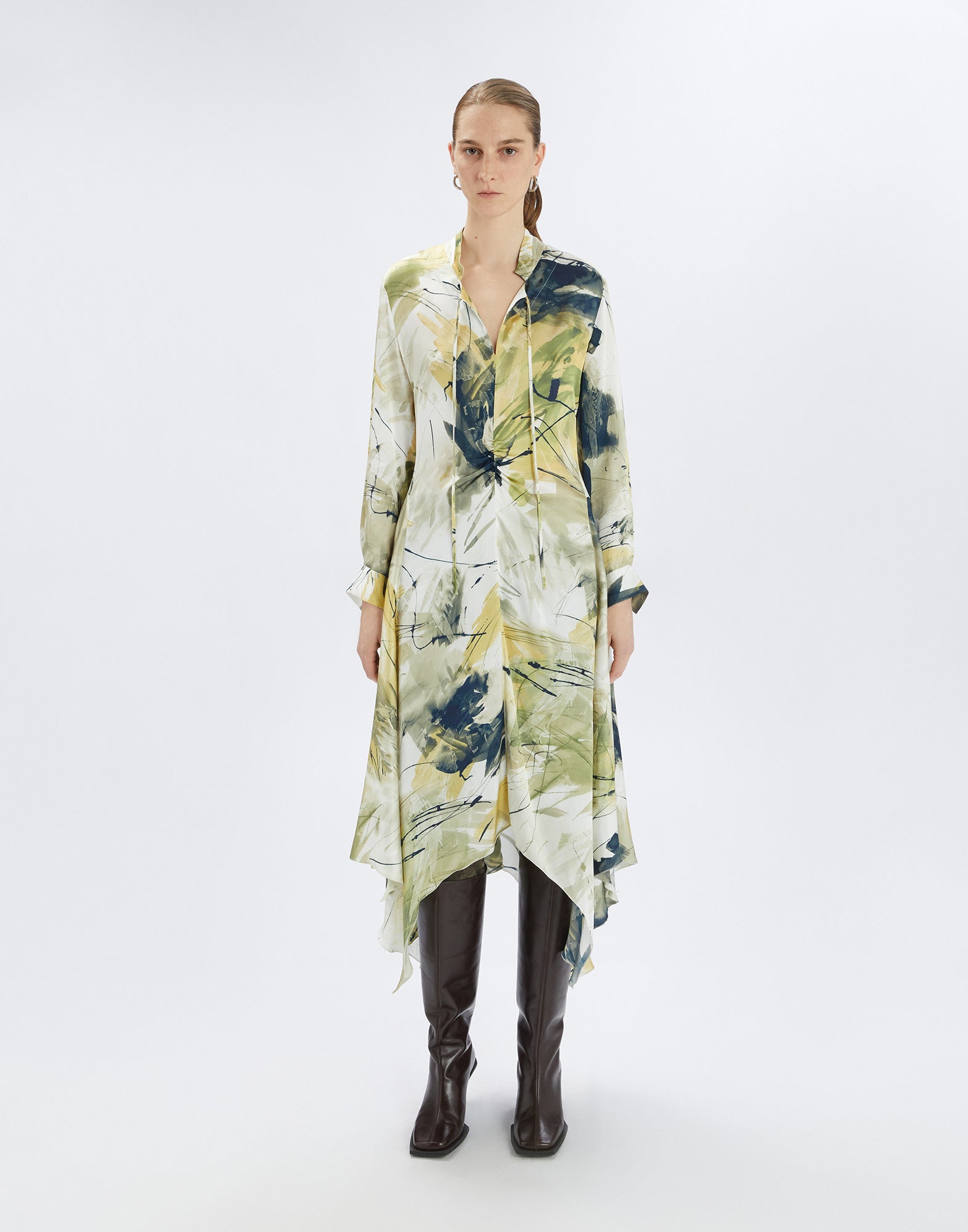 Front view: person wearing the abstract print FILO dress in yellow and green tones with uneven hem, long sleeves, and mandarin collar.