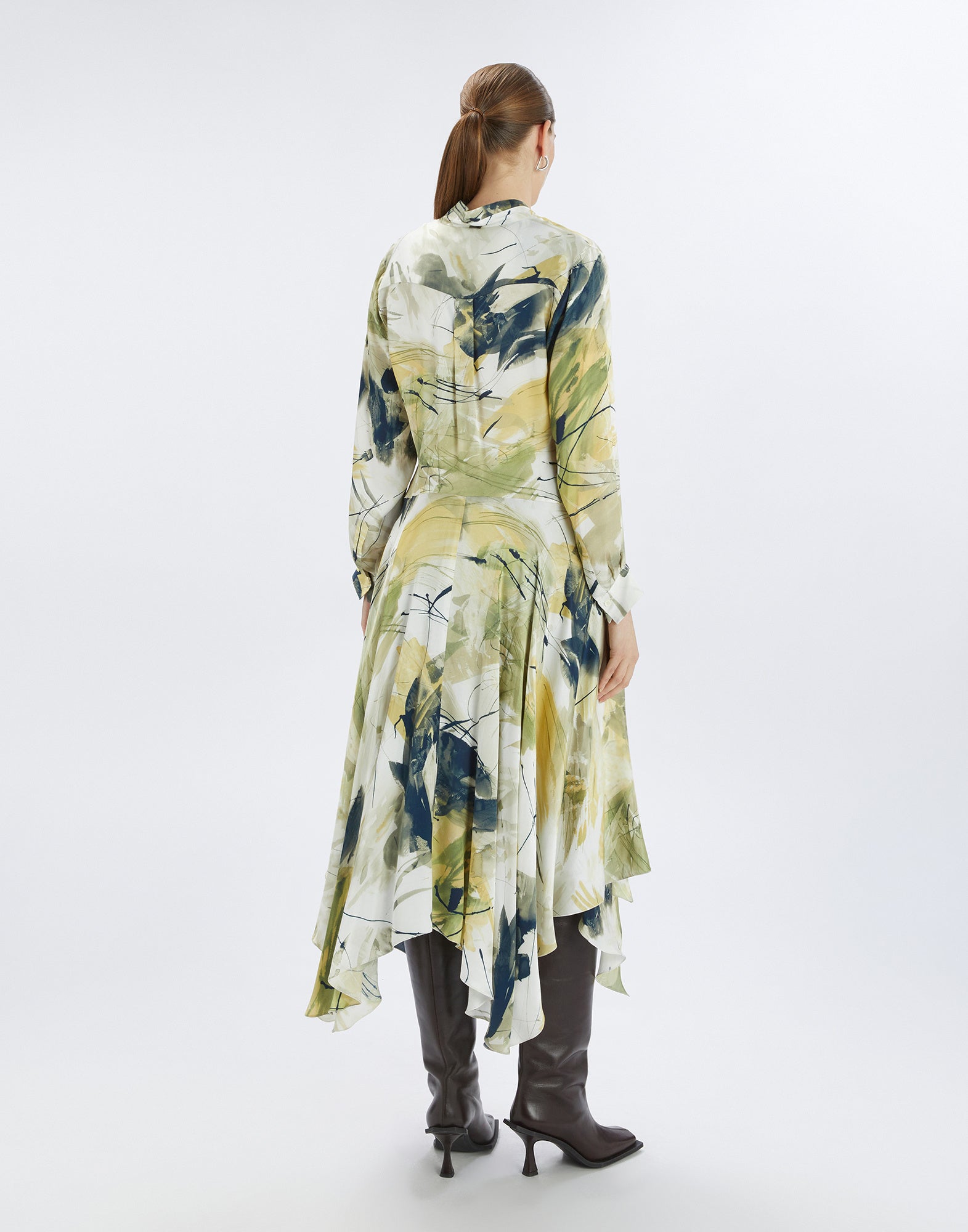 Rückansicht des FILO Kleides mit abstraktem, gelb-grünem Pinselstrichdruck, langen Ärmeln, asymmetrischem Saum und Falten am Rücken. Model steht aufrecht.