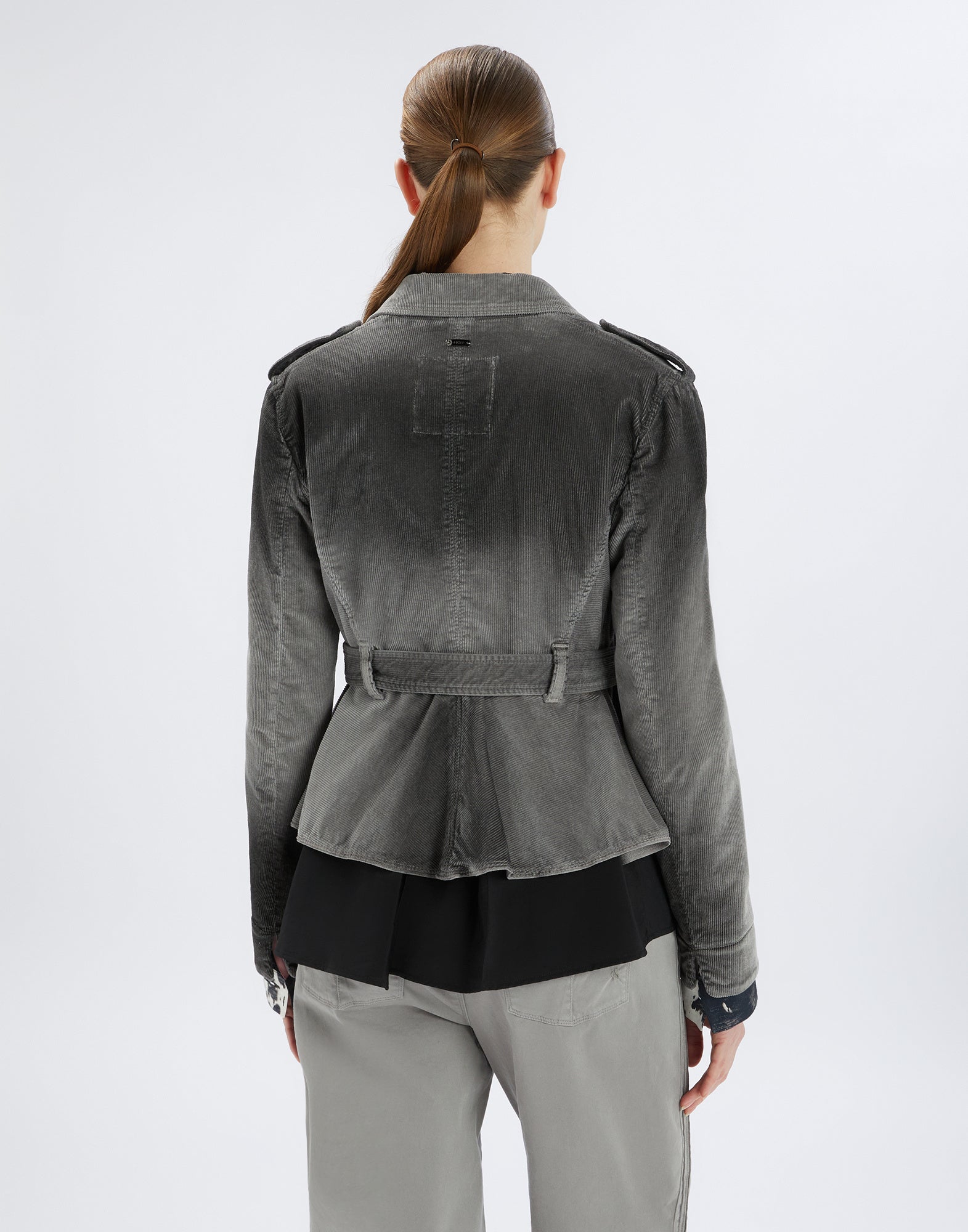 Back view of a person wearing the GIG biker jacket in corduroy. Shows a fitted cut with belt at hip height and shoulder epaulettes.
