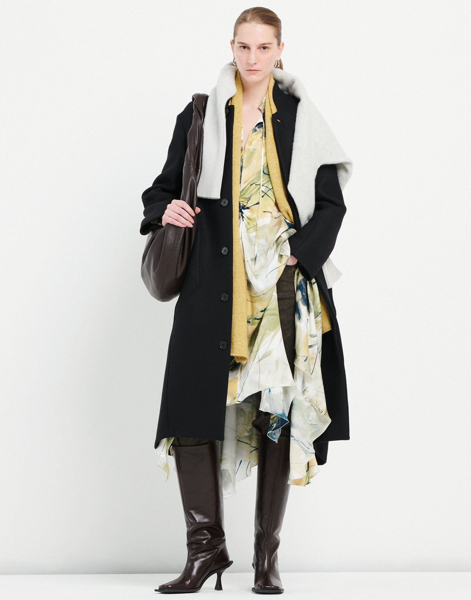 Front view: person wearing the PANTO coat in black with stand collar, visible buttons, and side seam pockets. The coat reaches the ankle.