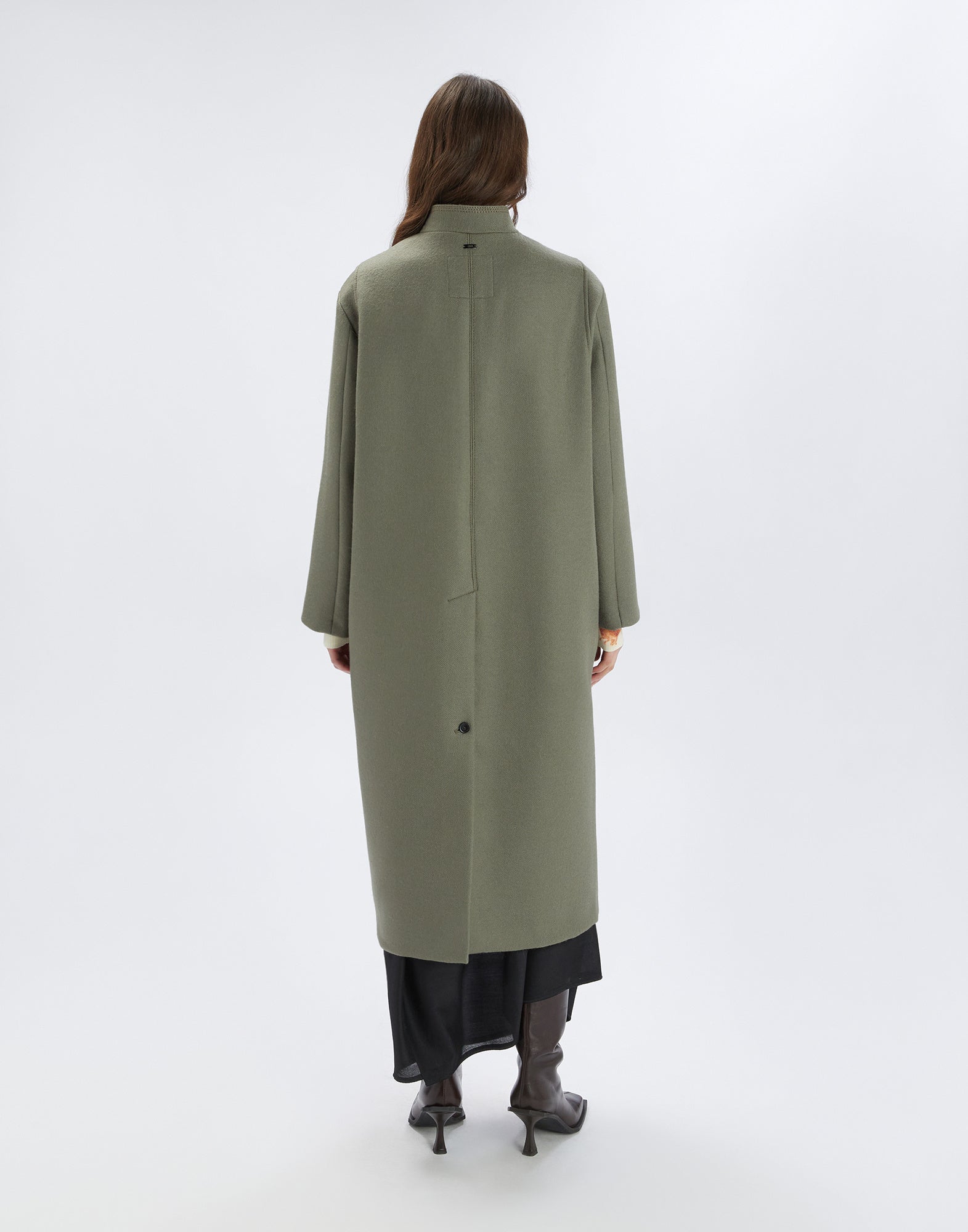 Back view of a person wearing the ankle-length, oversized PANTO coat with stand collar, central back vent, and button detail. Urban-chic design, long sleeves.