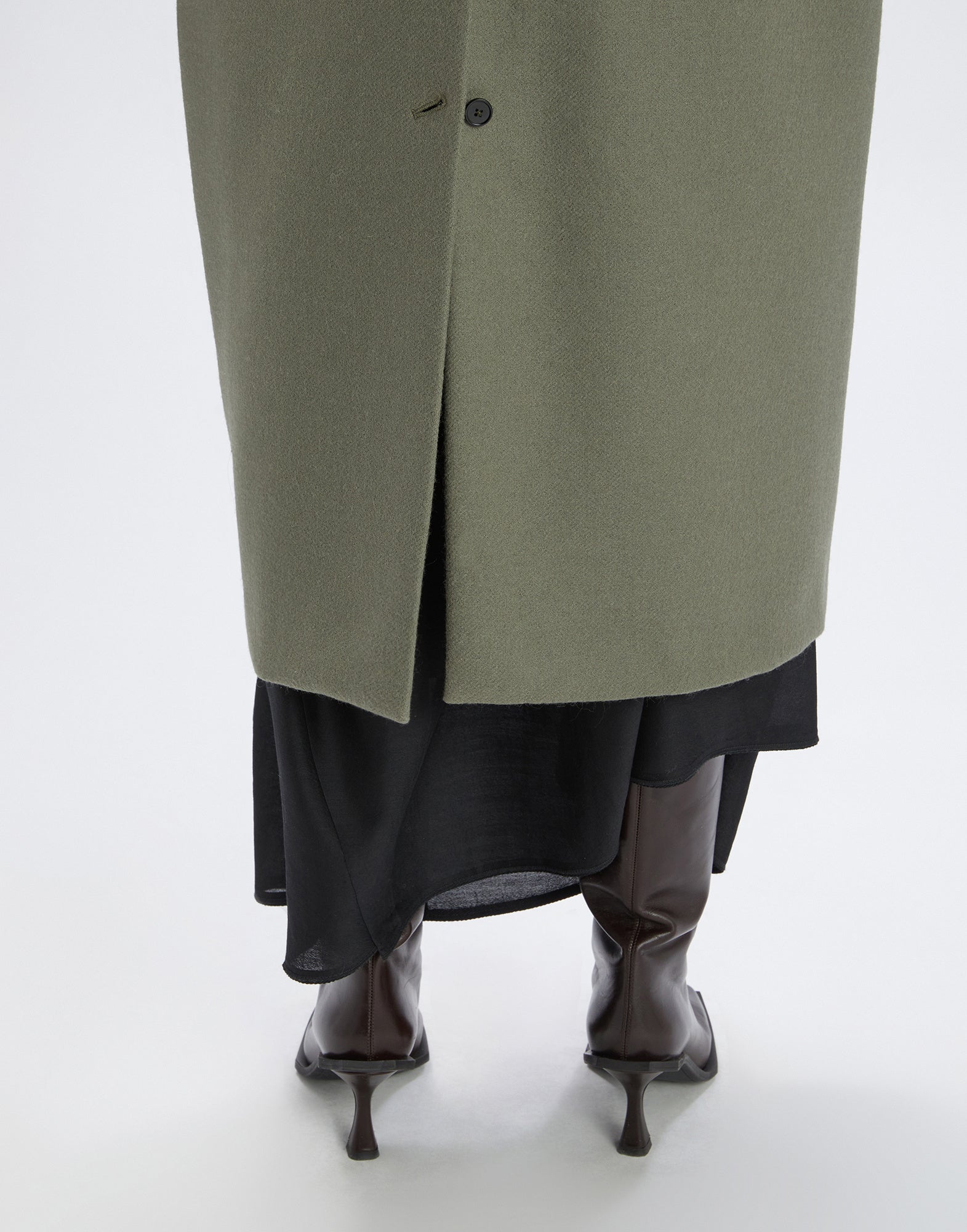 Back view: PANTO coat with vent and button closure, knee-high boots visible beneath the ankle-length, classic black fabric.