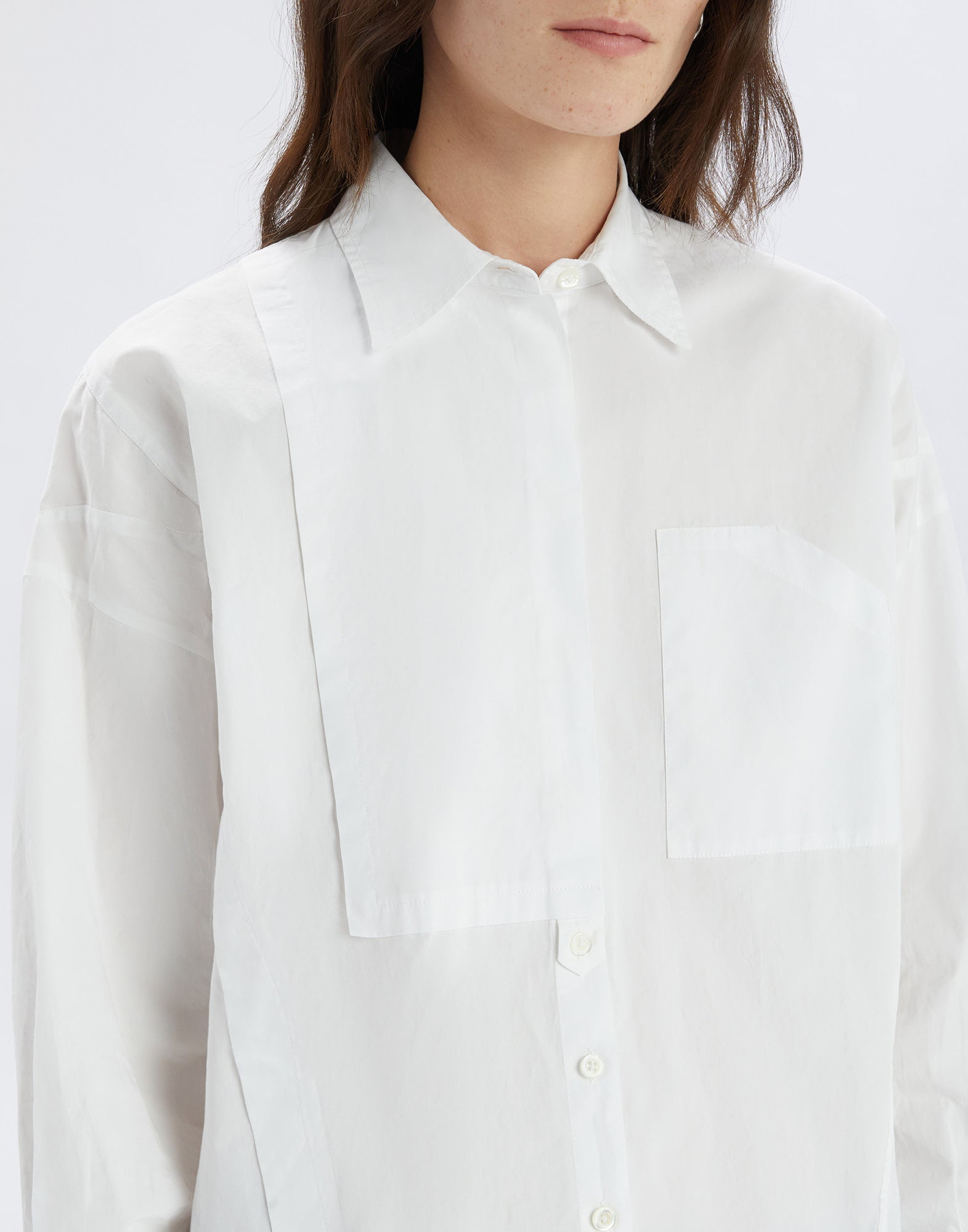 Front view: DEADLINE shirt in white cotton with turn-down collar, asymmetric front, chest pocket, and concealed button placket, worn by woman.