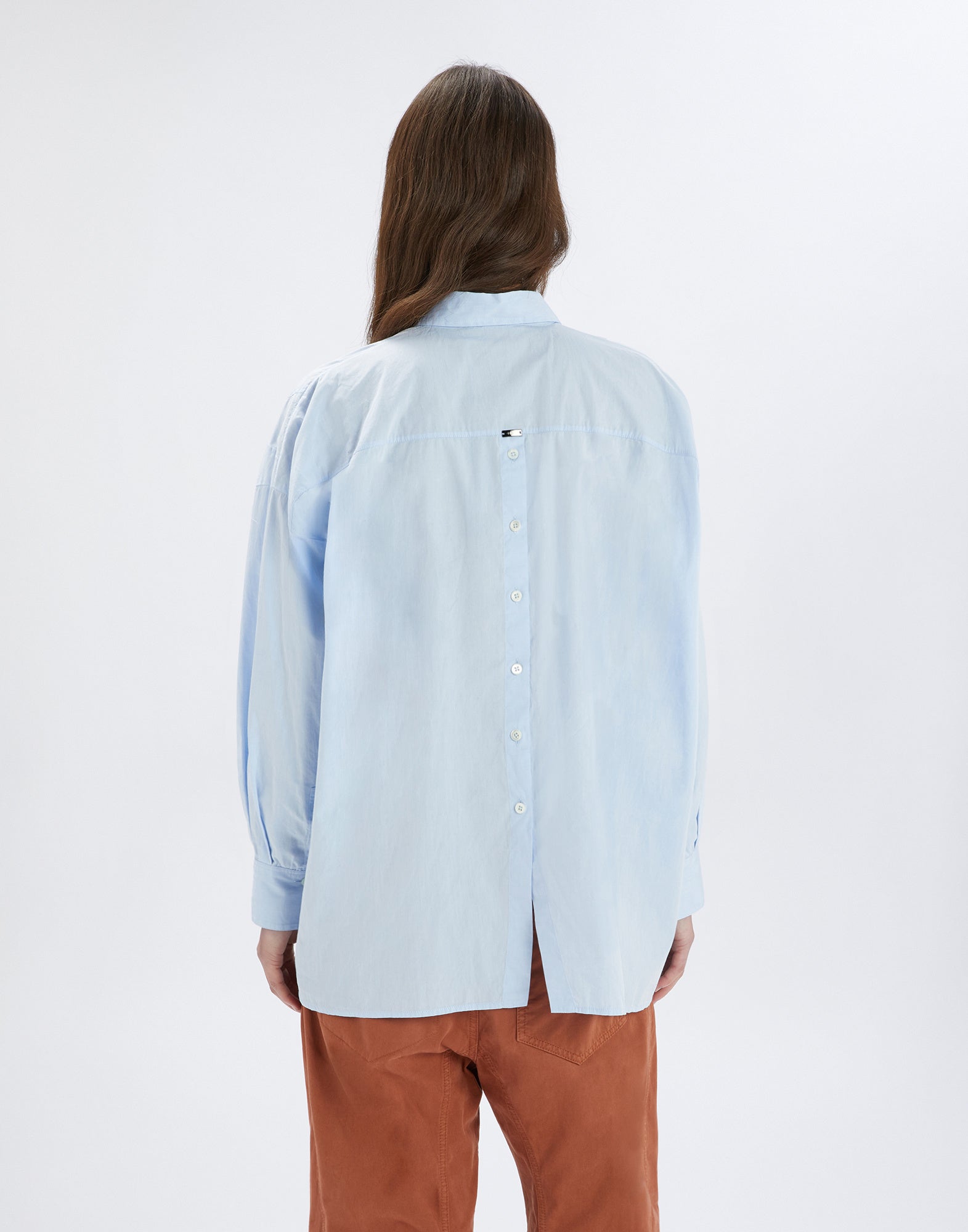 Rückansicht einer Person, die das DEADLINE Hemd in hellem Blau trägt; sichtbar sind der mittige Rückverschluss mit Knopfleiste und abgerundetem Saum.