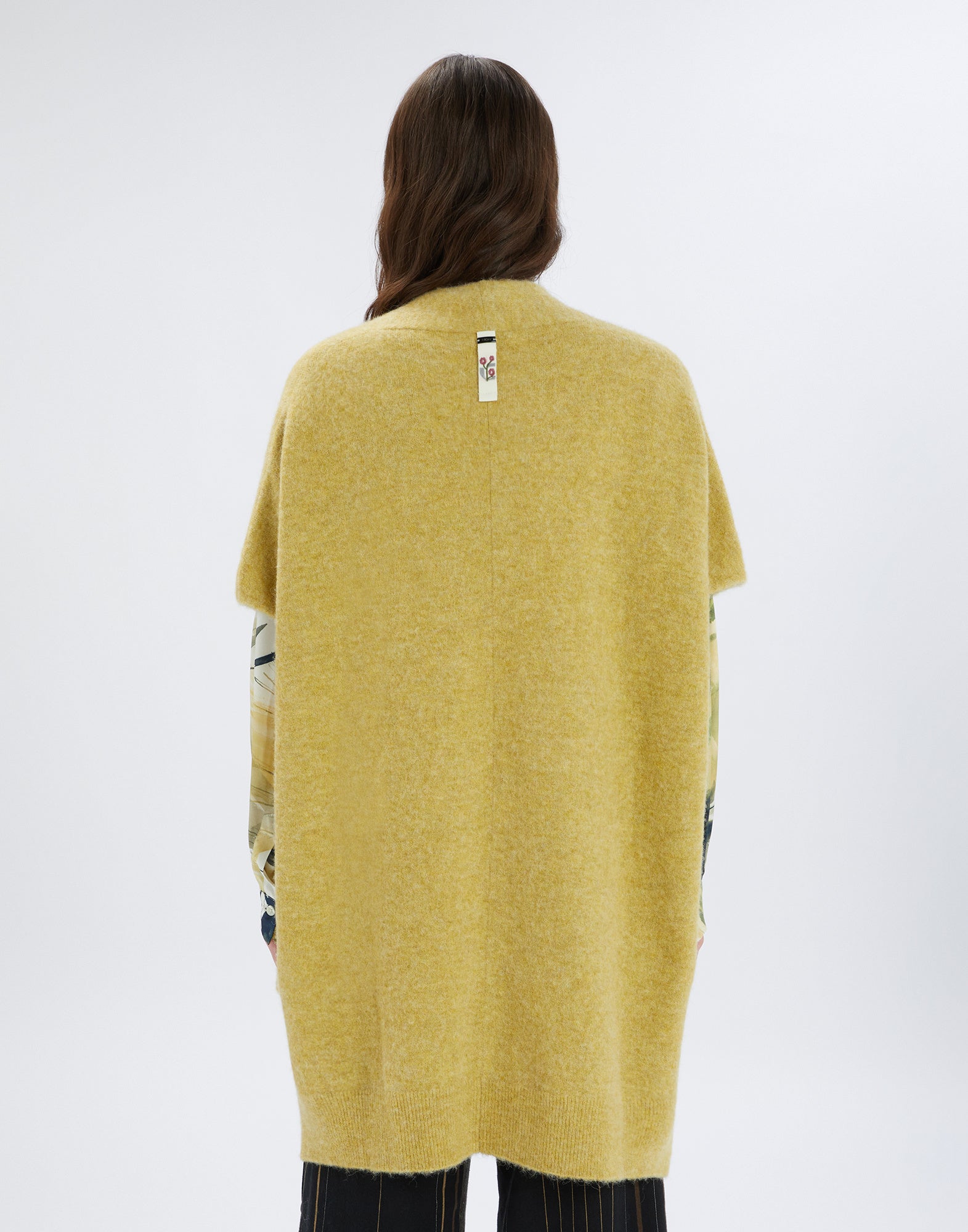 Back view of PRUDENCE, an open, medium-weight cape in yellow wool and alpaca with short sleeves, side slits, and an embroidered tab at the collar.