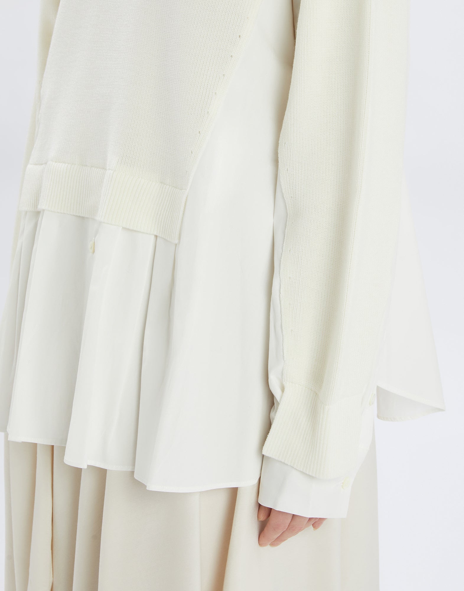 Detailansicht des HEART-BIT Pullis, Fokus auf die Rückenpartie und den Ärmel. Sichtbar ist der Mix aus feiner Wolle und Baumwollpopeline in Cremeweiß.