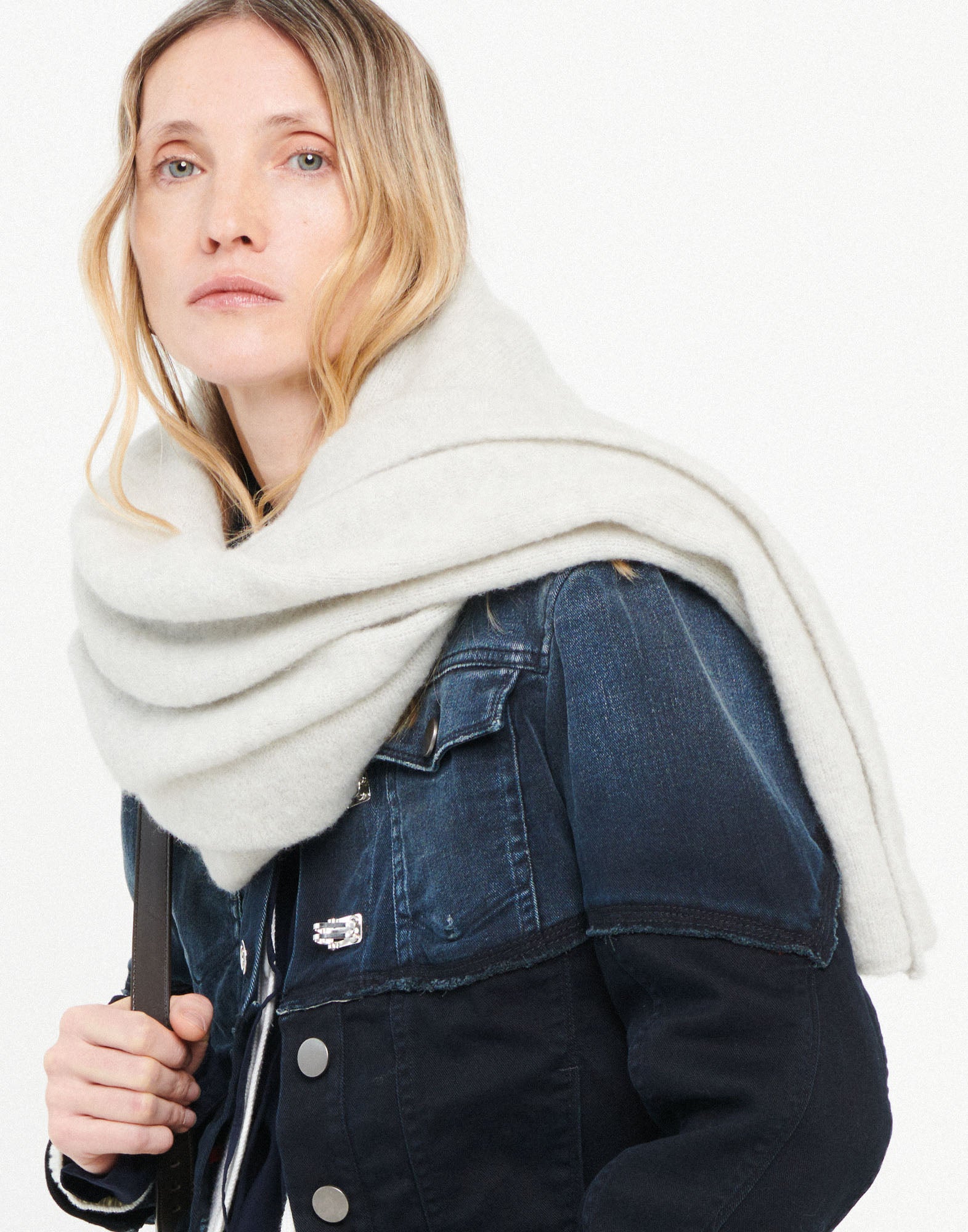 Front view: Woman wears the FROSTY stretch alpaca wool scarf in light white loosely around the neck, paired with a dark blue denim jacket.