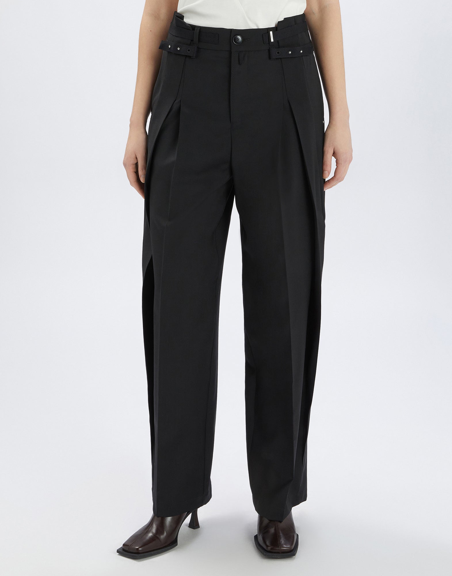 Front view of NEVERLAND pants in extra-fine black wool with double pleats, waistband with rivets and pleats, worn by woman.