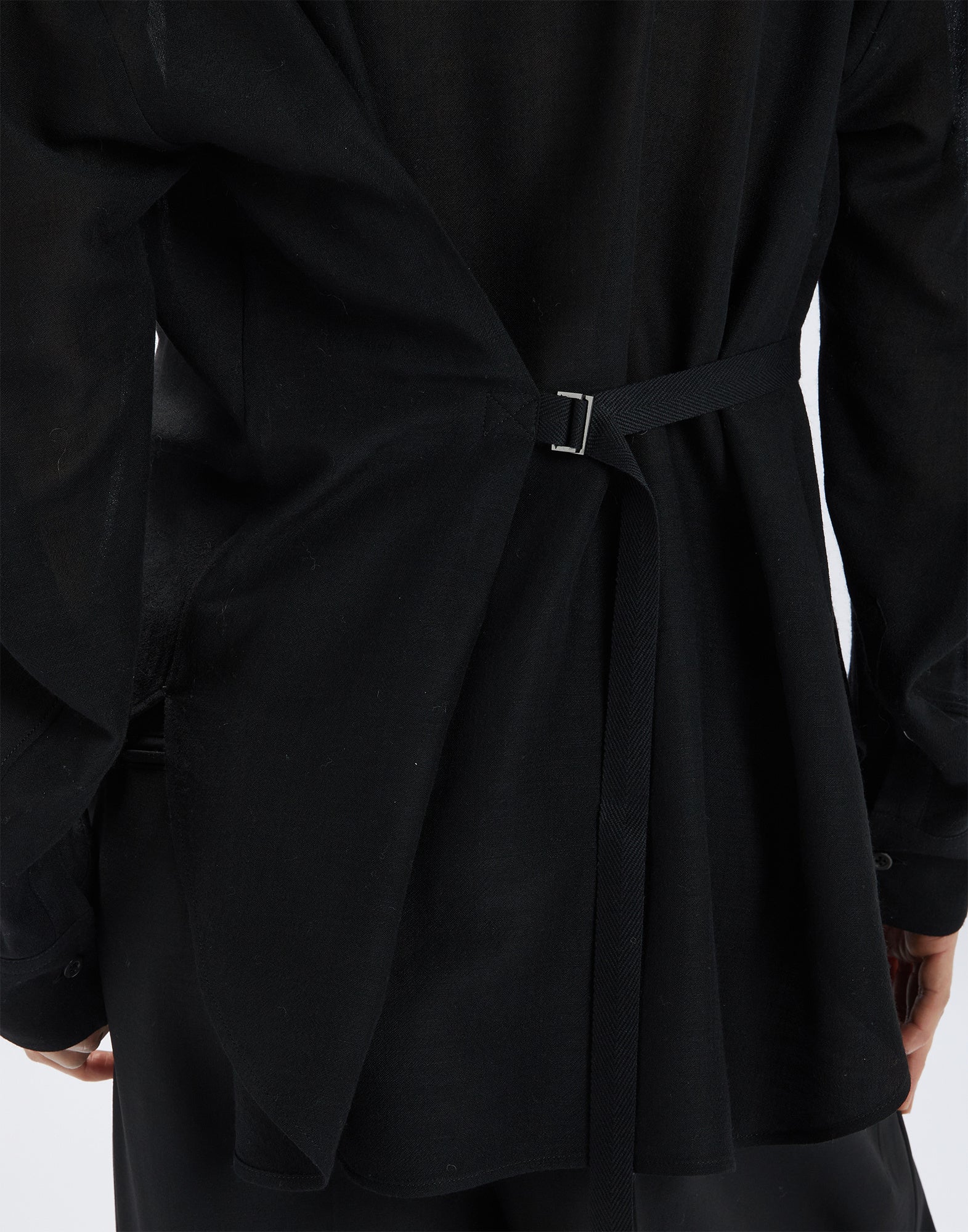 Back view of the SCOOT blouse showing the D-ring for fit adjustment with a slim band on an almost transparent, black wool gauze fabric.