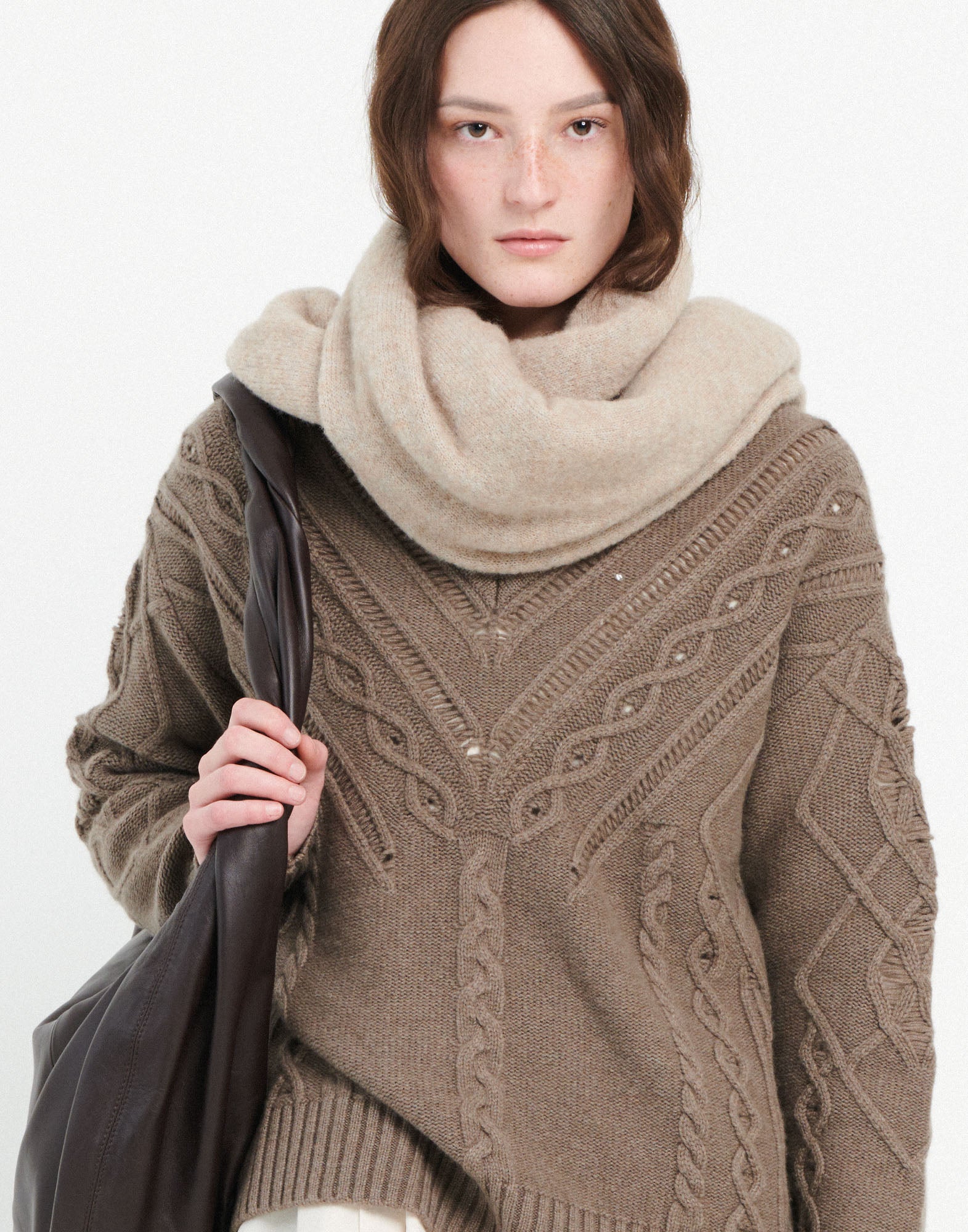 Frontalansicht einer Person, die den NORTON Pullover trägt; breites Zopf- und Ajourmuster, gerippter V-Ausschnitt, lockere Schultern, braun meliert.