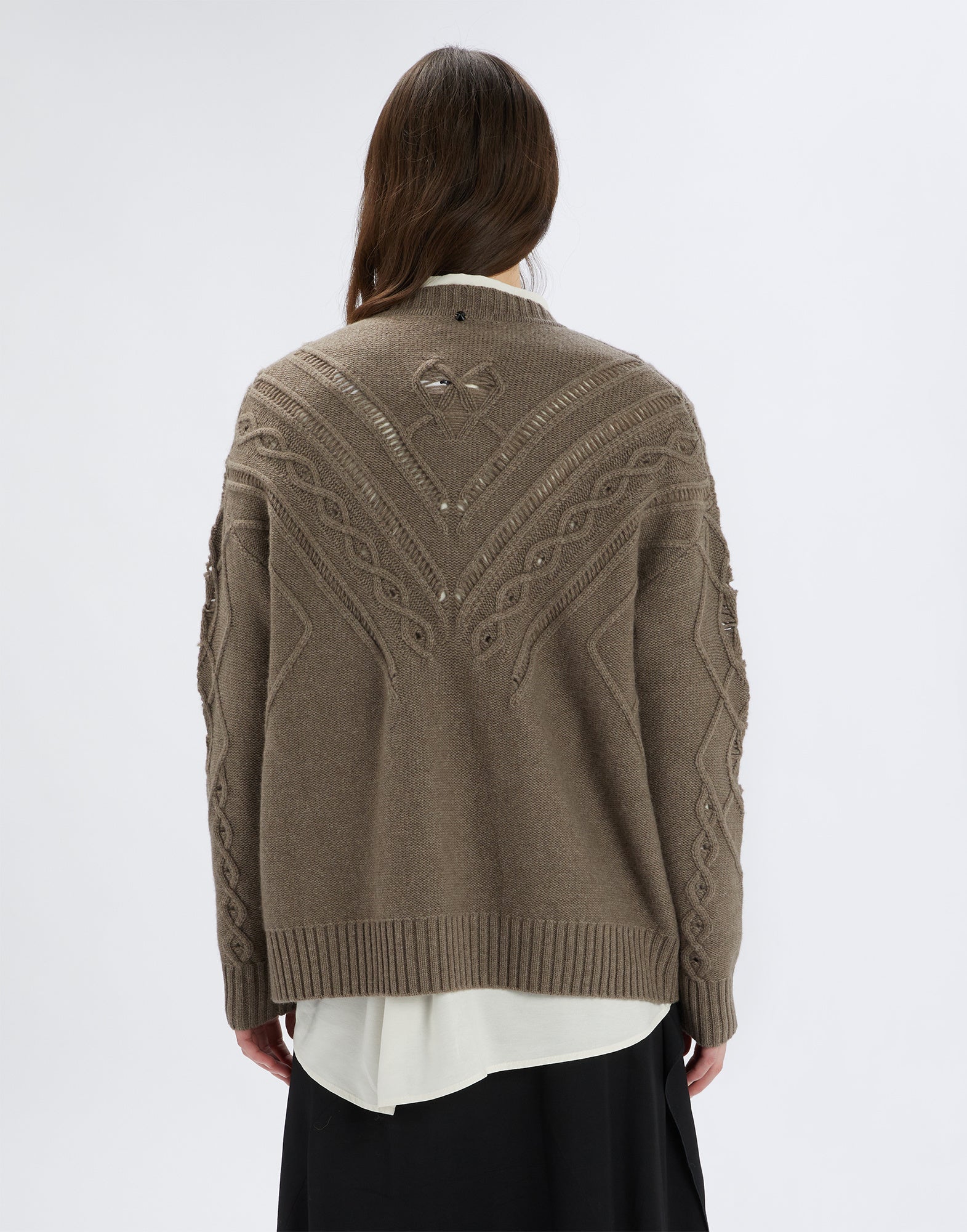 Rückansicht einer Person, die den NORTON Pullover trägt. Sichtbar sind breite Rippen, diagonale Ajour- und Zopfmuster sowie ein Swarovski-Kristall auf der Rückseite.