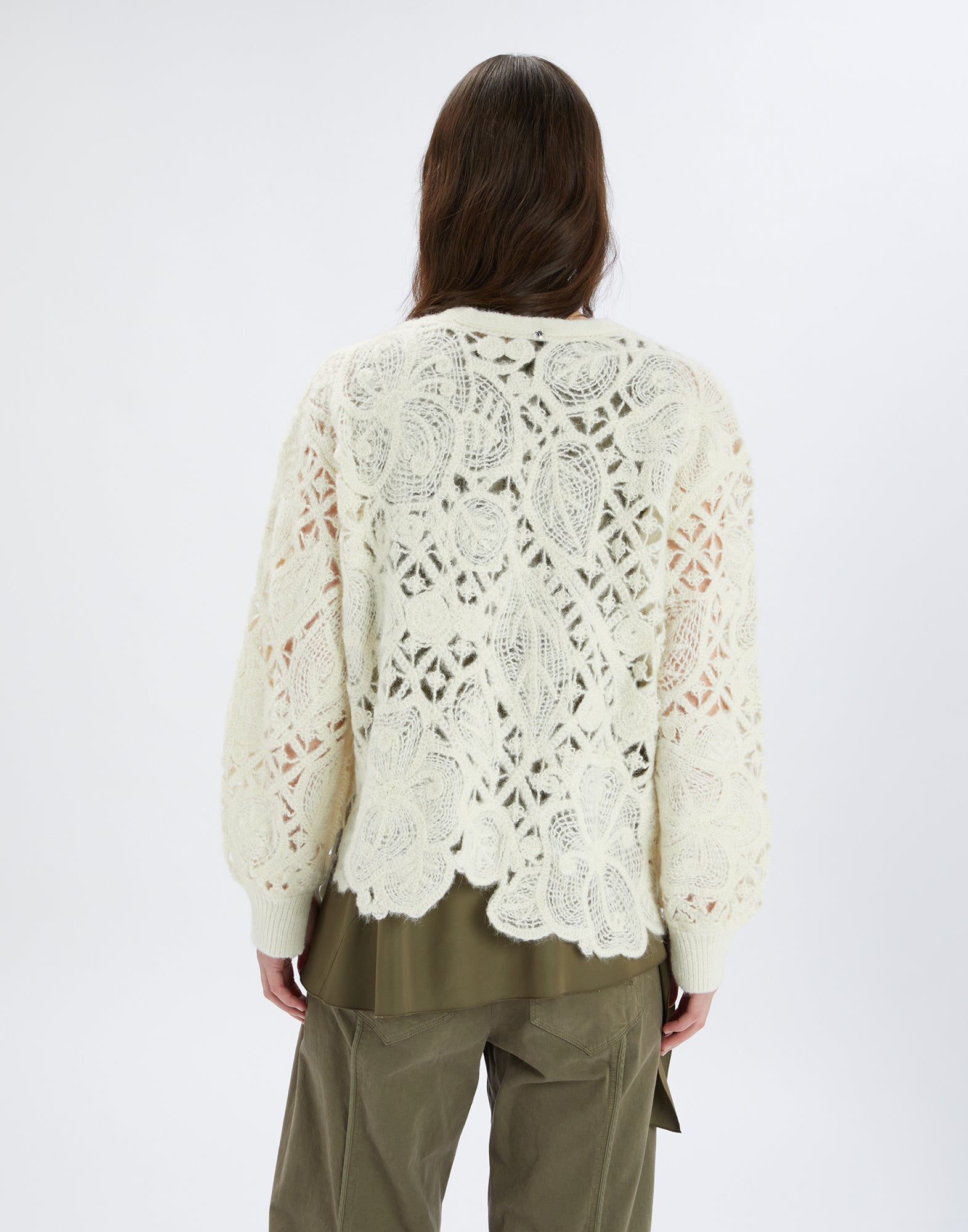 Back view of a person wearing the BOHEME cardigan with floral openwork embroidery and asymmetric hem. The knit pattern is cream-colored and looks delicate.