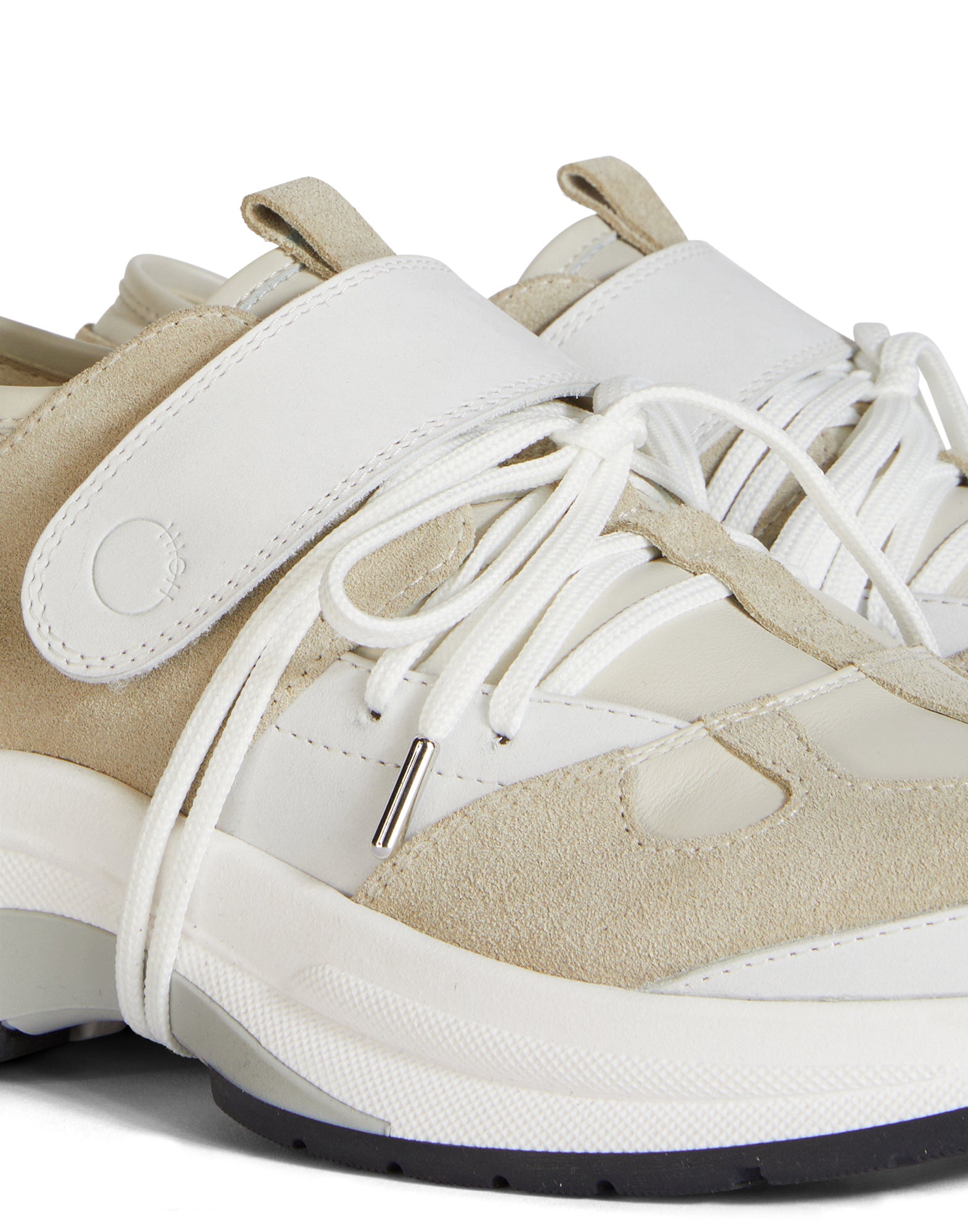 Close-up view of the PARTIAL sneaker, shown from the front. Tonal leather types, white laces, Velcro strap, and heat-stamped logo on the tongue clearly visible.