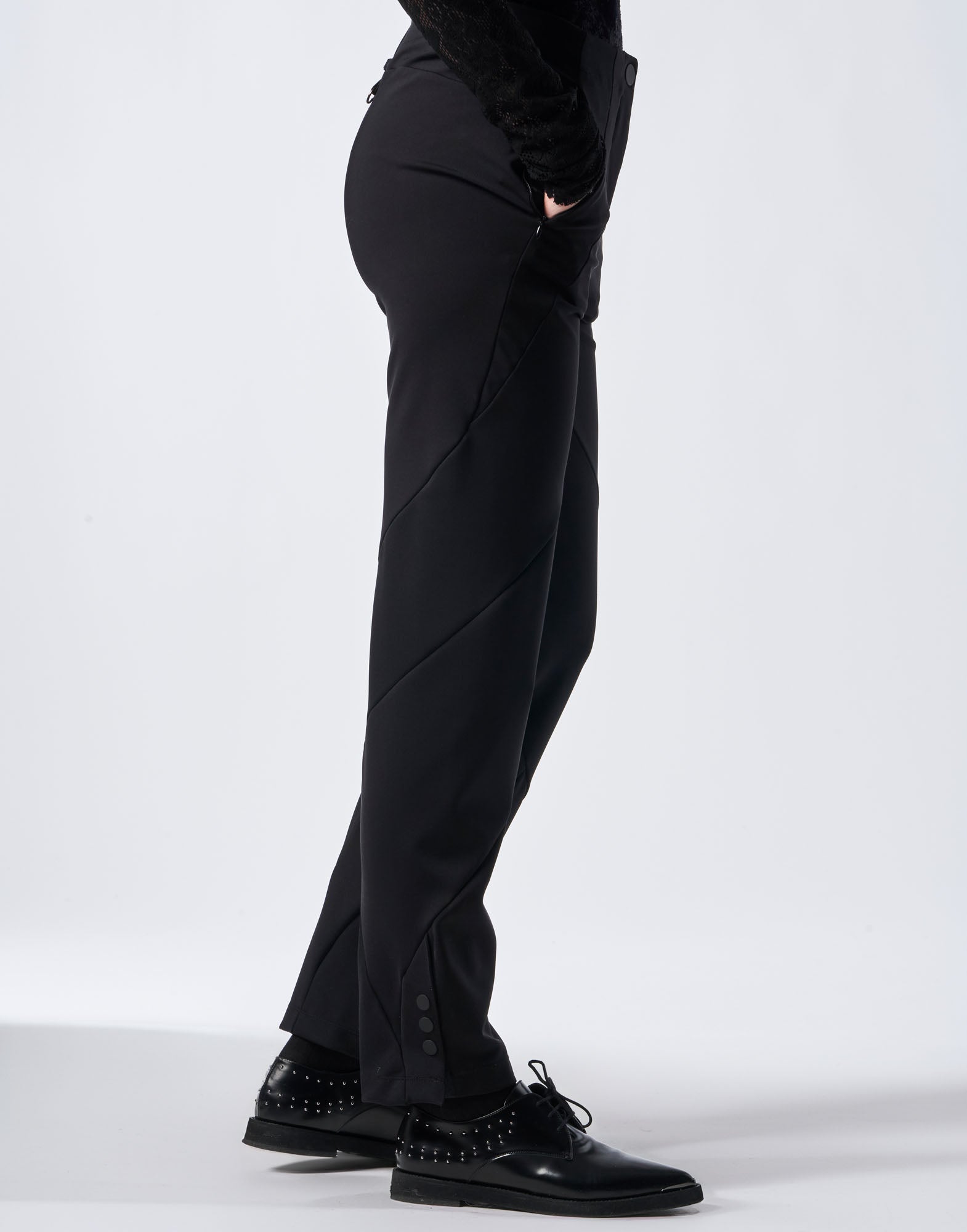Side view of JOLT pants, slim fit, black, in smooth neoprene jersey with distinctive spiral seams and snap button details at the hem.