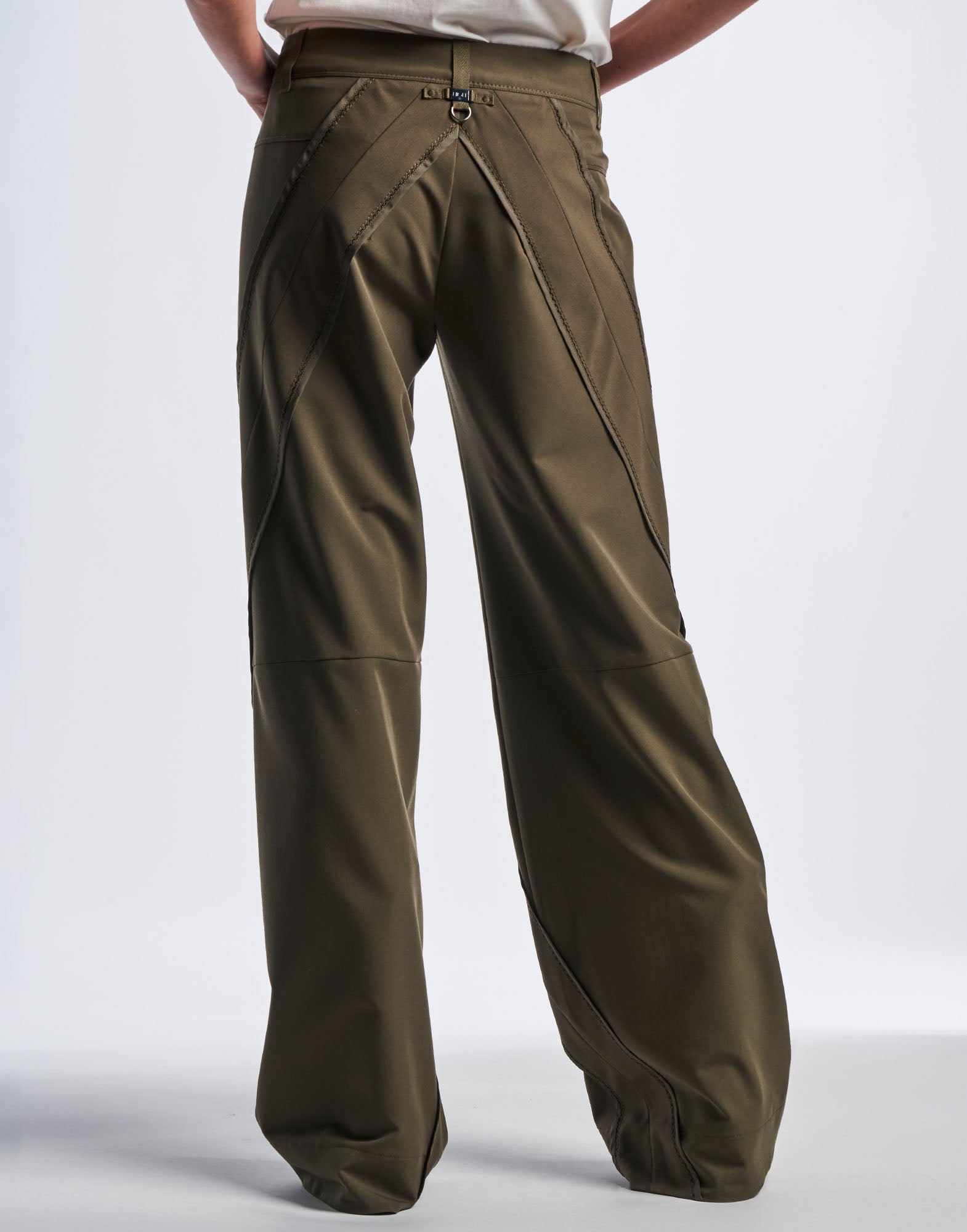 Rückansicht der GRAVITATE Hose mit weit geschnittenem Bein aus olivfarbenem Funktionstwill, markanten diagonalen Nähten und breitem Saum, getragen von einer Person.