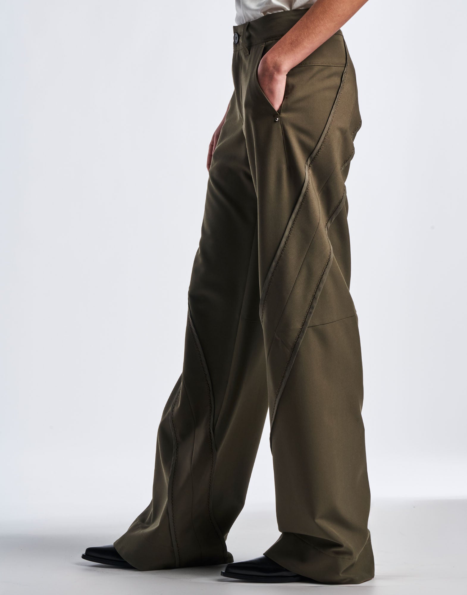 Seitenansicht der GRAVITATE Hose mit weit geschnittenem Bein. Sichtbar sind schräge Einsätze, schlichte Gürtelschlaufen, Knopf am Bund und diagonale Nähte.