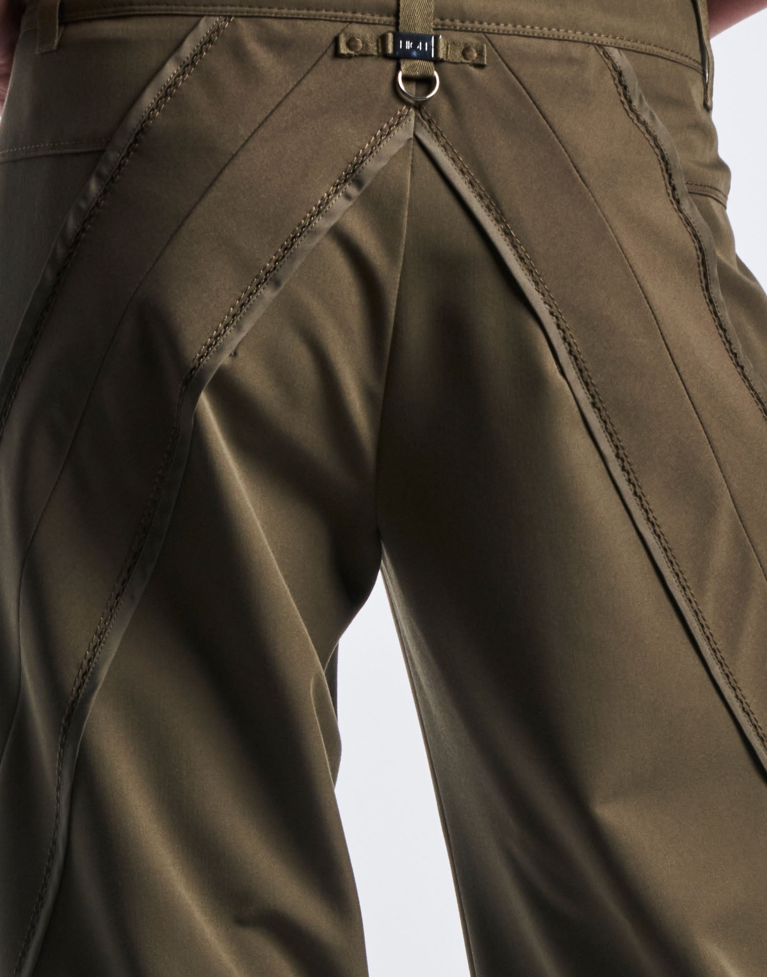 Detailansicht von hinten: Hose GRAVITATE mit weitem Bein, markanten Zickzack-Kettstichnähten und eingesetzten Stoffteilen aus olivgrünem Funktionstwill.