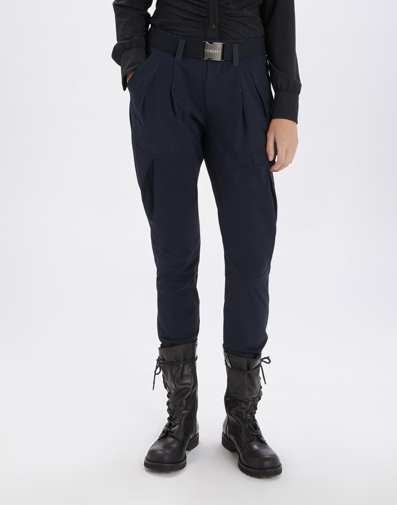 Front view of a person wearing the LURCH jodhpur pants in dark blue, paired with a black shirt, visible elastic belt, and black boots.