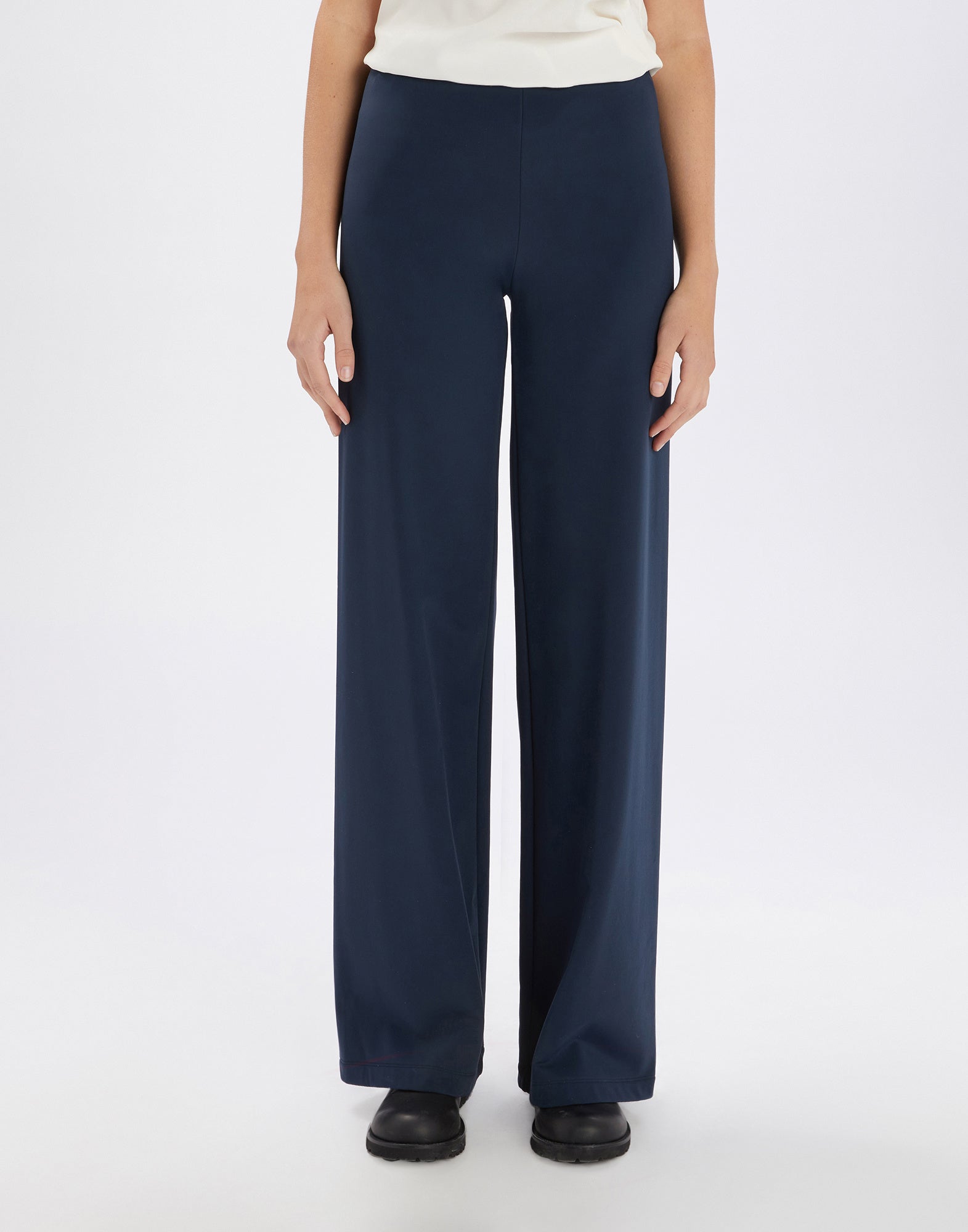 Front view of the MARCH pants, high-waisted with wide leg, in dark blue, without visible pockets or seams, worn with black shoe.