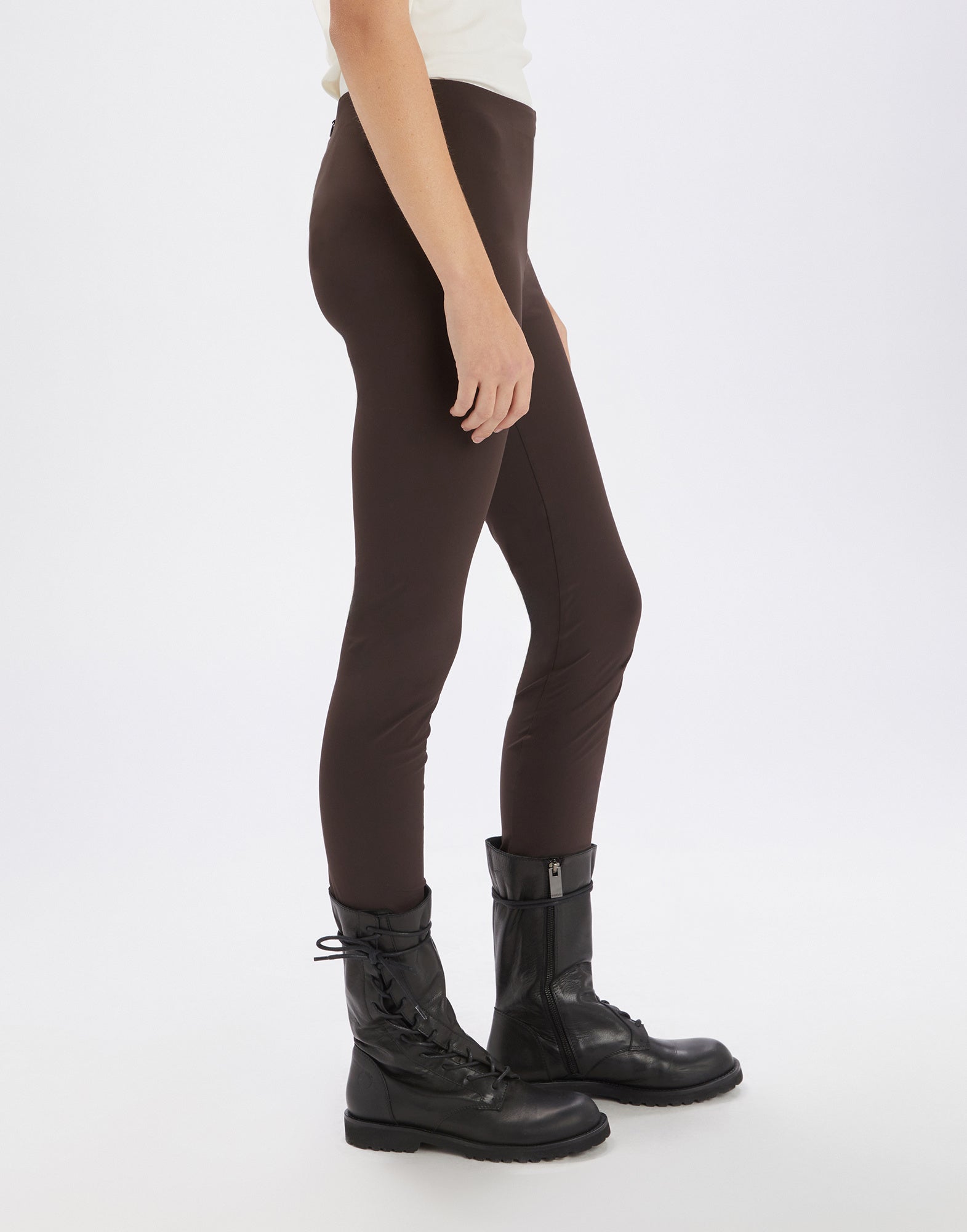Side view of brown JEEPERS leggings with no visible seams or pockets, featuring an elastic waistband and high cuffs at the hem, worn by model.