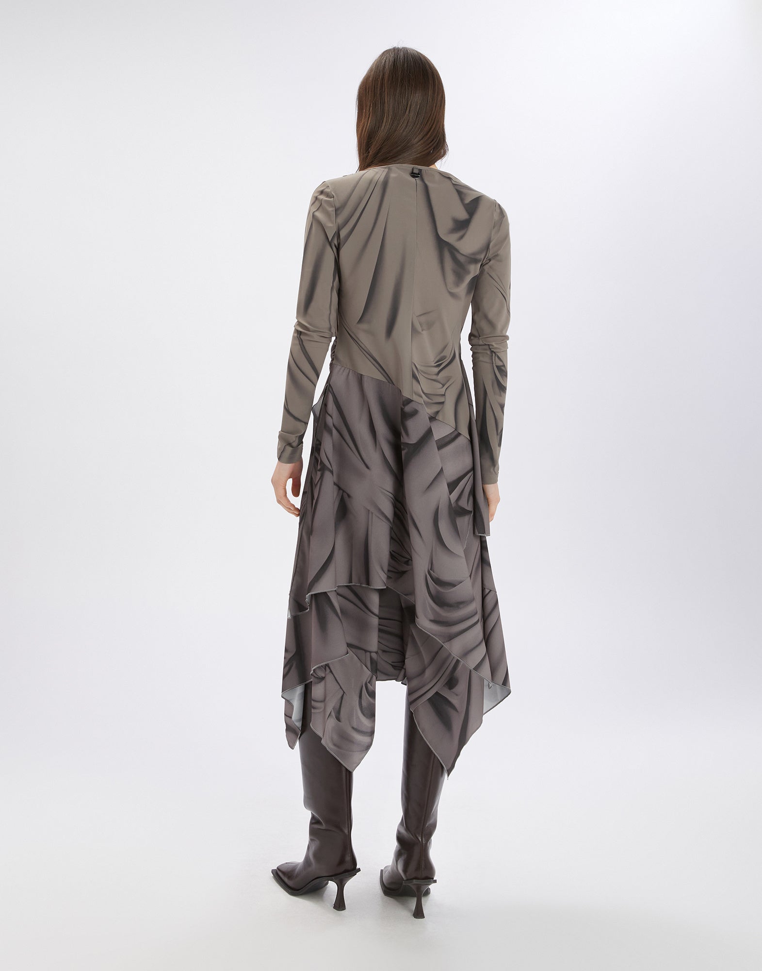 Back view of TROUPE dress worn by a person, featuring long sleeves, asymmetric hem, and graphic Drapery motif, paired with boots.