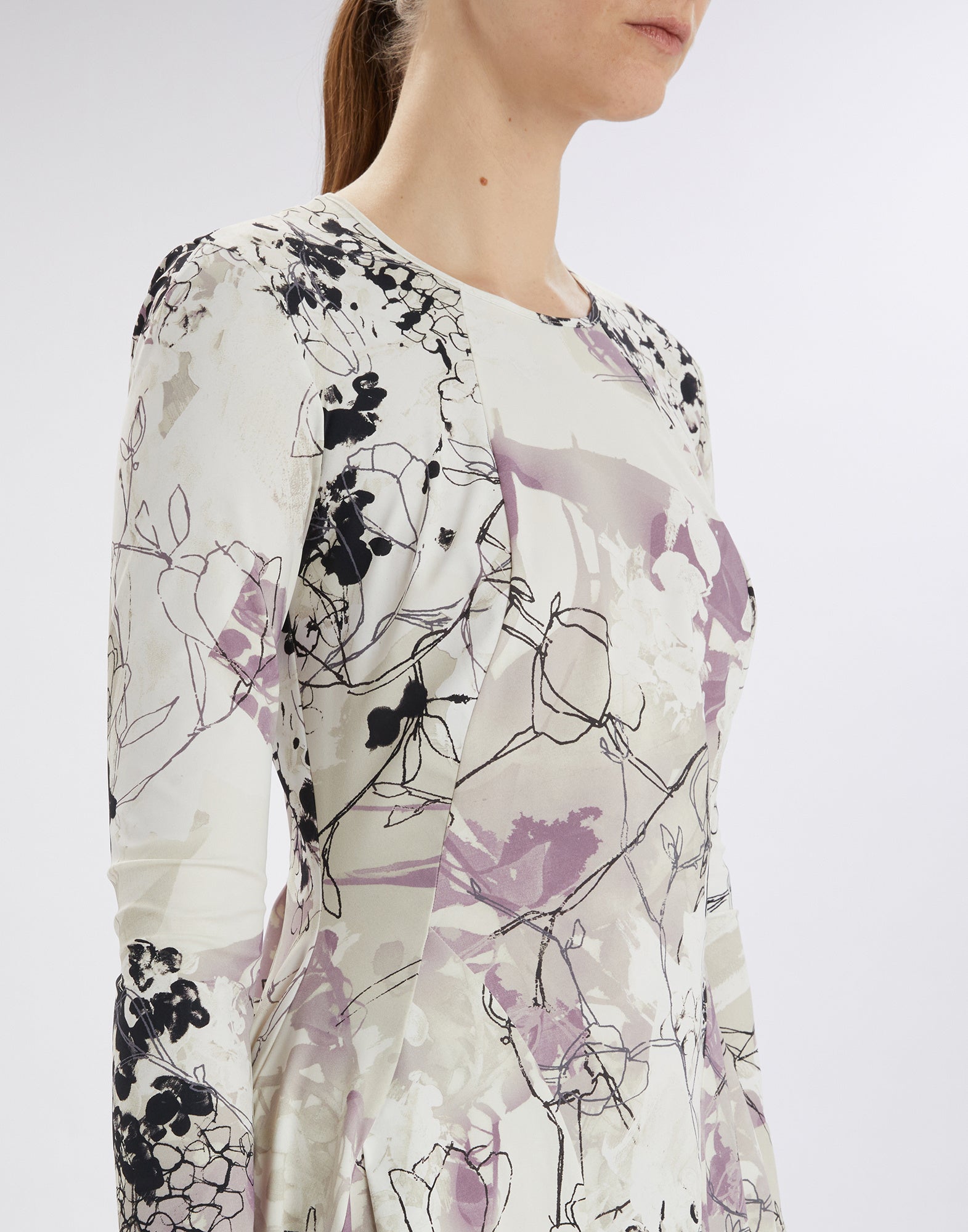 Close-up front view: model wears the AT-LENGTH dress with Layered Flowers print in light and violet tones, fitted at the bodice.