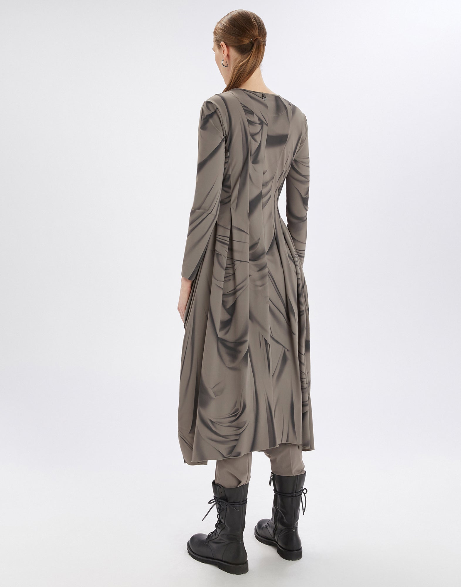 Rückansicht einer Person, die das AT-LENGTH Kleid trägt; das langärmlige, gemusterte Kleid mit Ballonform und künstlerischem Drapery-Druck reicht bis unterhalb der Knie.