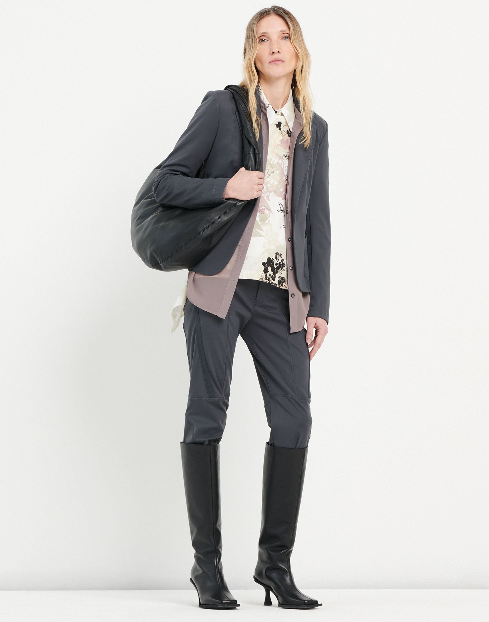Front view of a woman wearing the NO-WAY blazer in dark grey compact knit scuba fabric with raw-cut edges, exposed seams, and padded shoulders.
