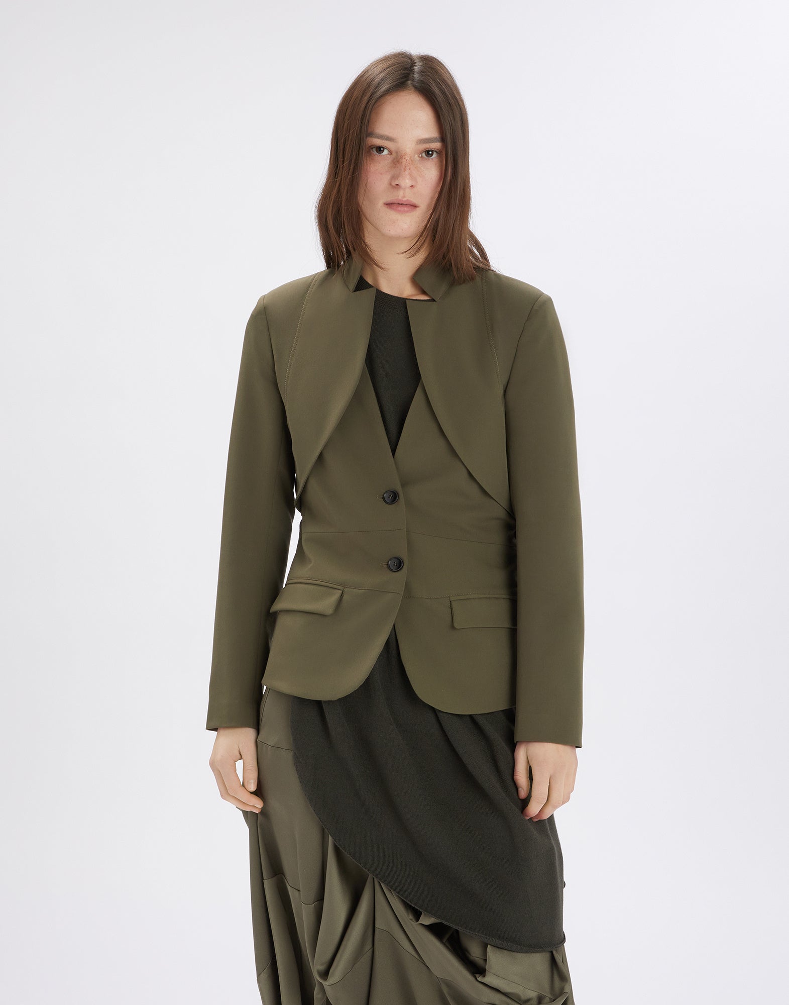 Front view of the PARALLAX jacket worn by a model. The jacket features an inverted notched collar, visible seams, and a geometric neckline.