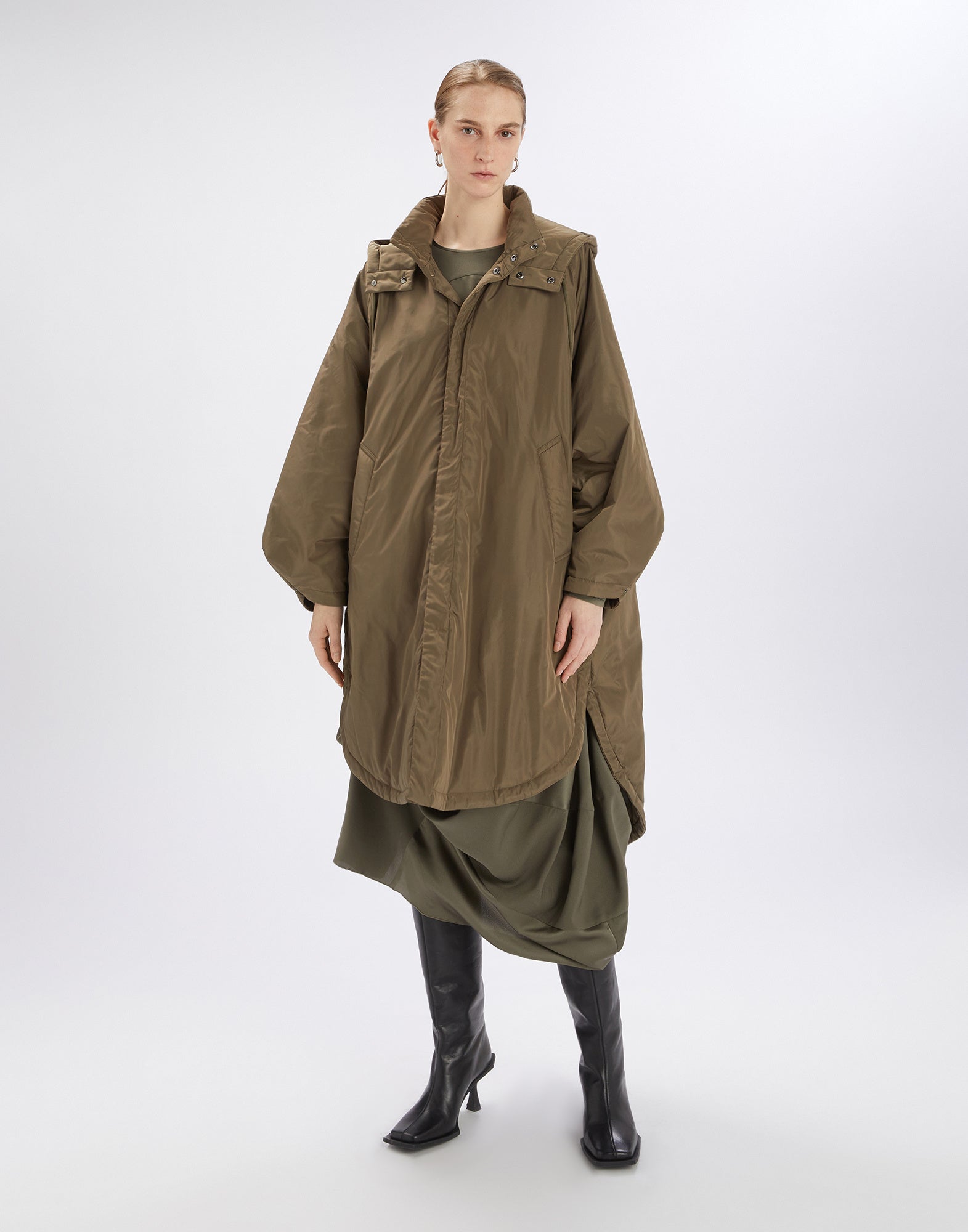 Frontalansicht: Eine Frau trägt den Parka COFFER in Khaki mit Oversize-Passform, weitem Schnitt, Kimono-Ärmeln, Stehkragen und verdecktem Frontverschluss.