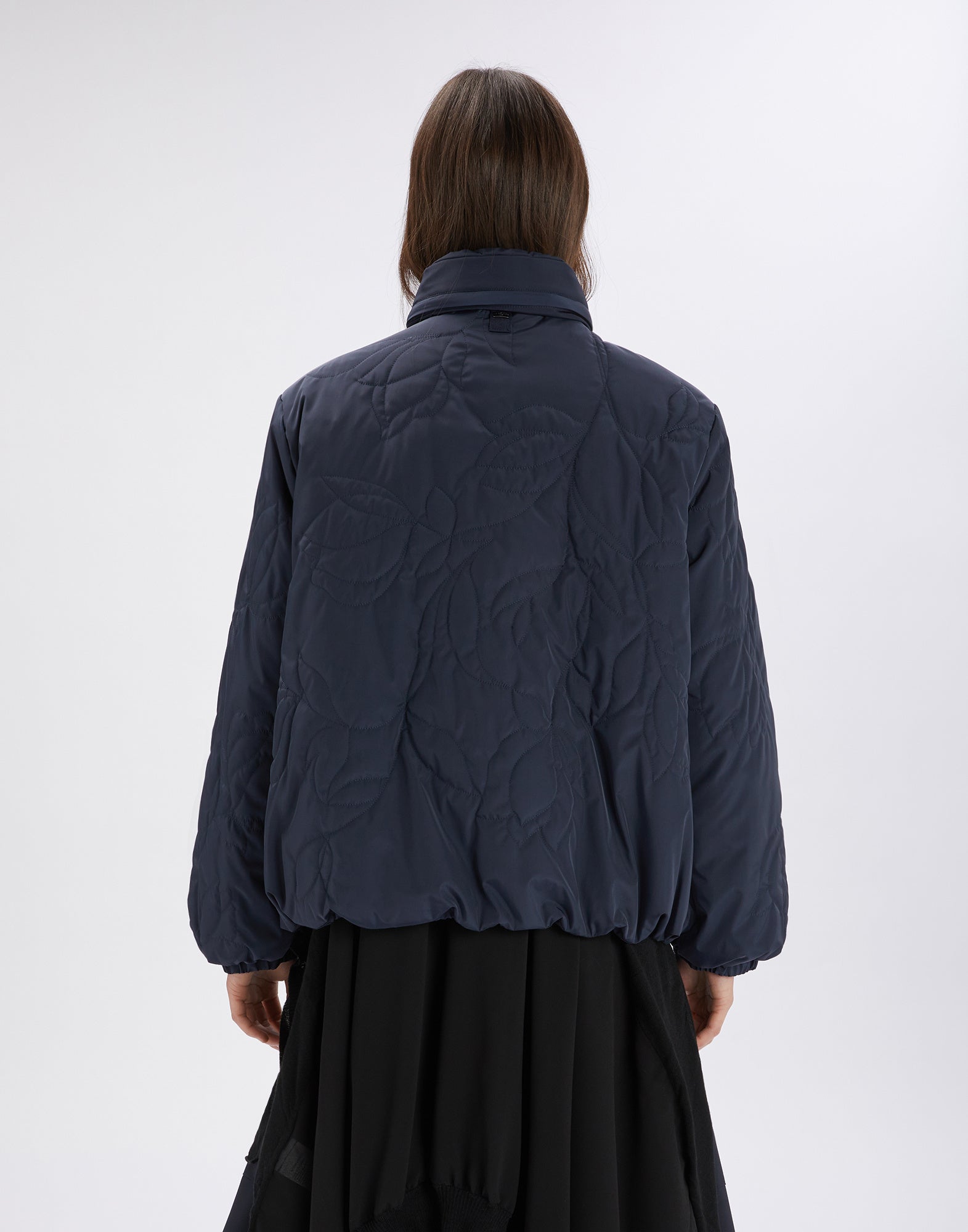 Rückansicht einer Person, die die BLURT Jacke trägt; die sportliche, wattierte Jacke aus wasserdichtem Nylon weist florale, dreidimensionale Steppstickereien auf.