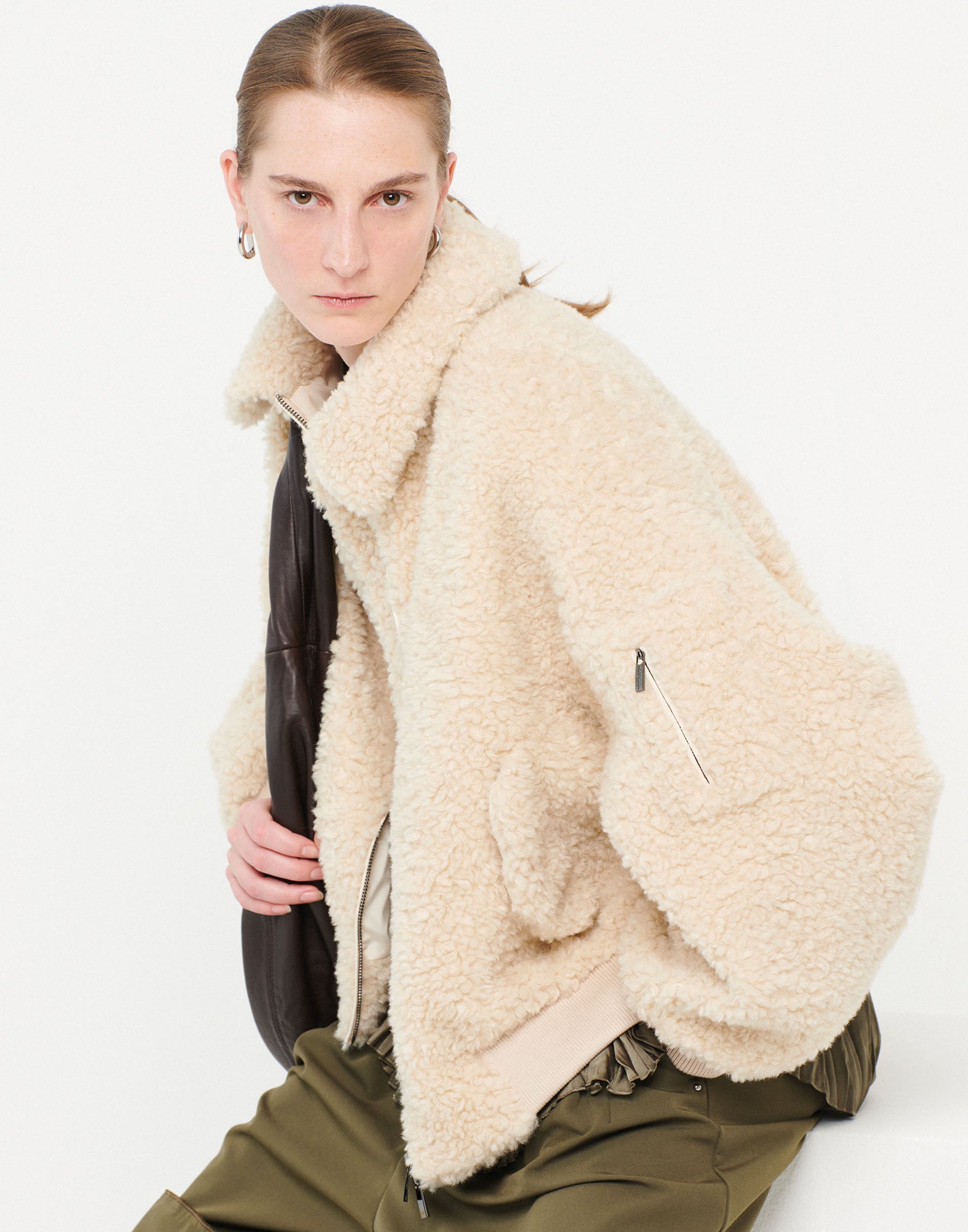 Front view: Person wears the RULER Sherpa bomber in cream-colored soft bouclé faux-shearling fabric with oversized fit, turned-down collar, and large flap pockets.