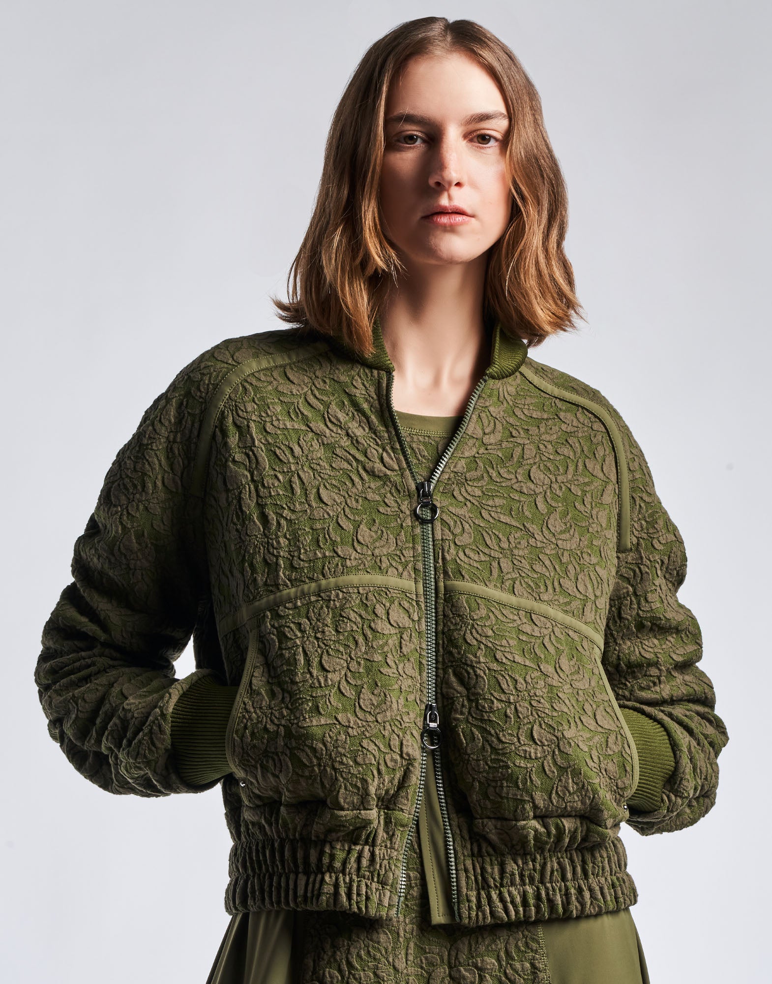 Front view: person wears the BOAST bomber jacket in floral jacquard cotton-blend jersey in military green with baseball collar, two-way zip, and elastic waistband.