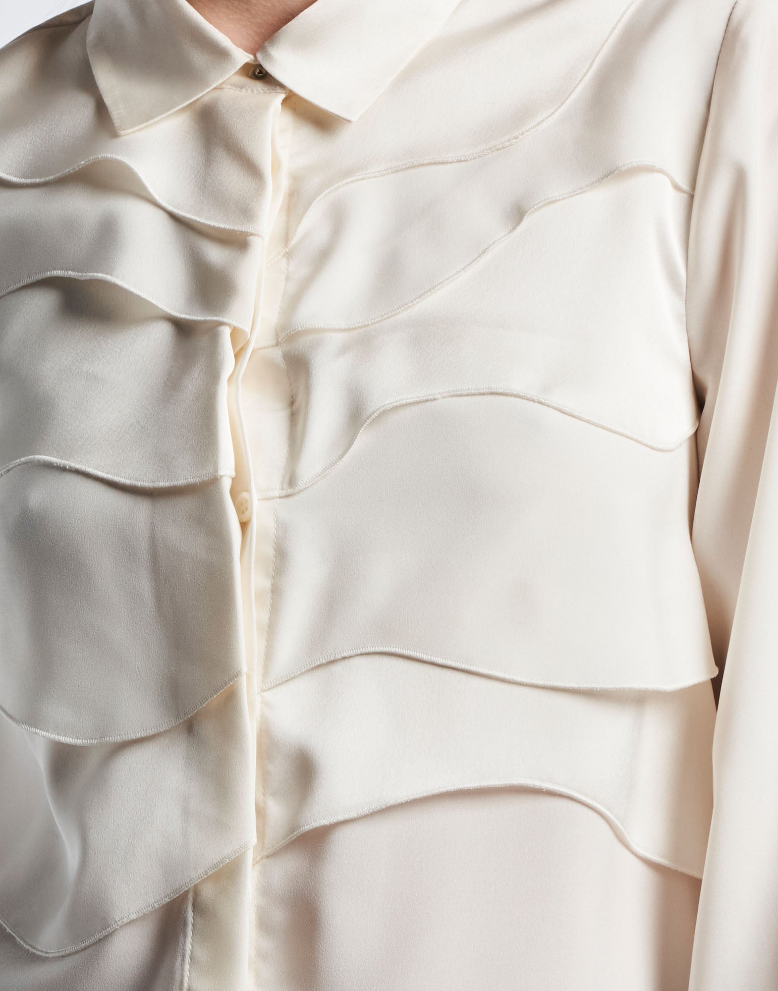 Close-up view of the ALTERNATE blouse, front-facing, shows curved alternating matte and shiny layers on the front made of satin-back crepe fabric.