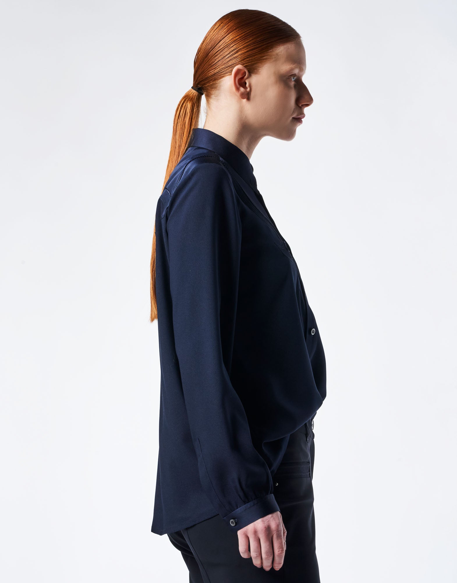 Side view of a person wearing the APPRECIATION blouse in Western style. The blouse features alternating matte and shiny panels and a longer back hem.