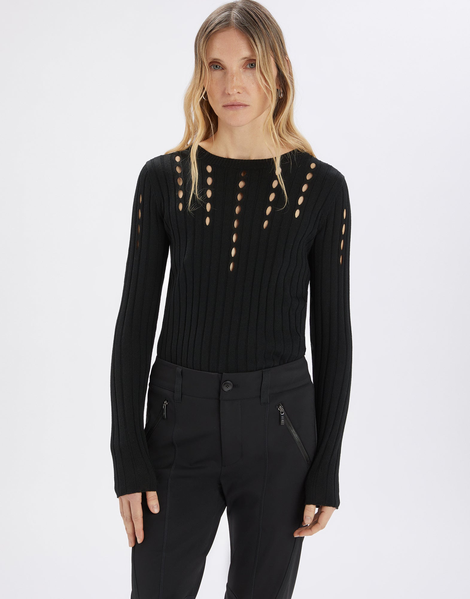 Front view: A woman wears the TATUM crewneck sweater in black ribbed knit with vertical cut-out openings at the front and on the sleeves.