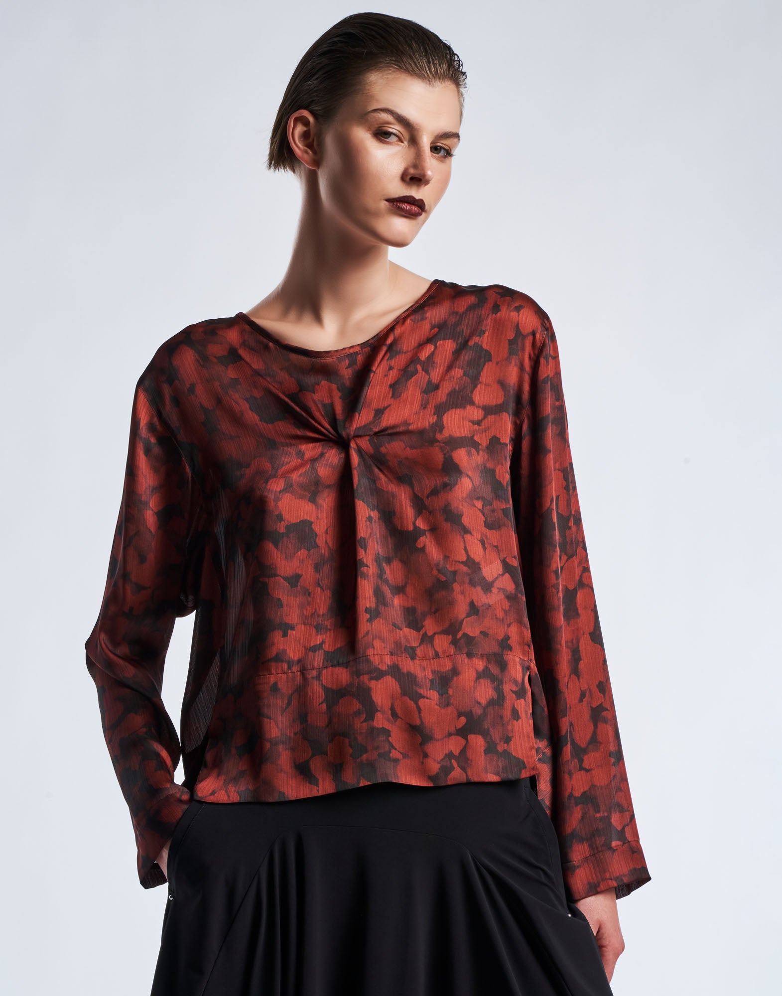 Front view: A person wears the ALONE top in technical crepon with black and claret red digital Geo Animalier print, wide neckline, and long sleeves.