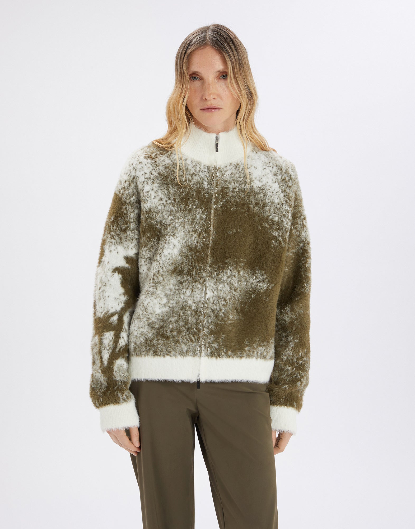 Front view: Woman wears SUMMON UP cardigan, oversized, two-tone jacquard in white and olive, with stand collar, zipper, and floral pattern on right sleeve.