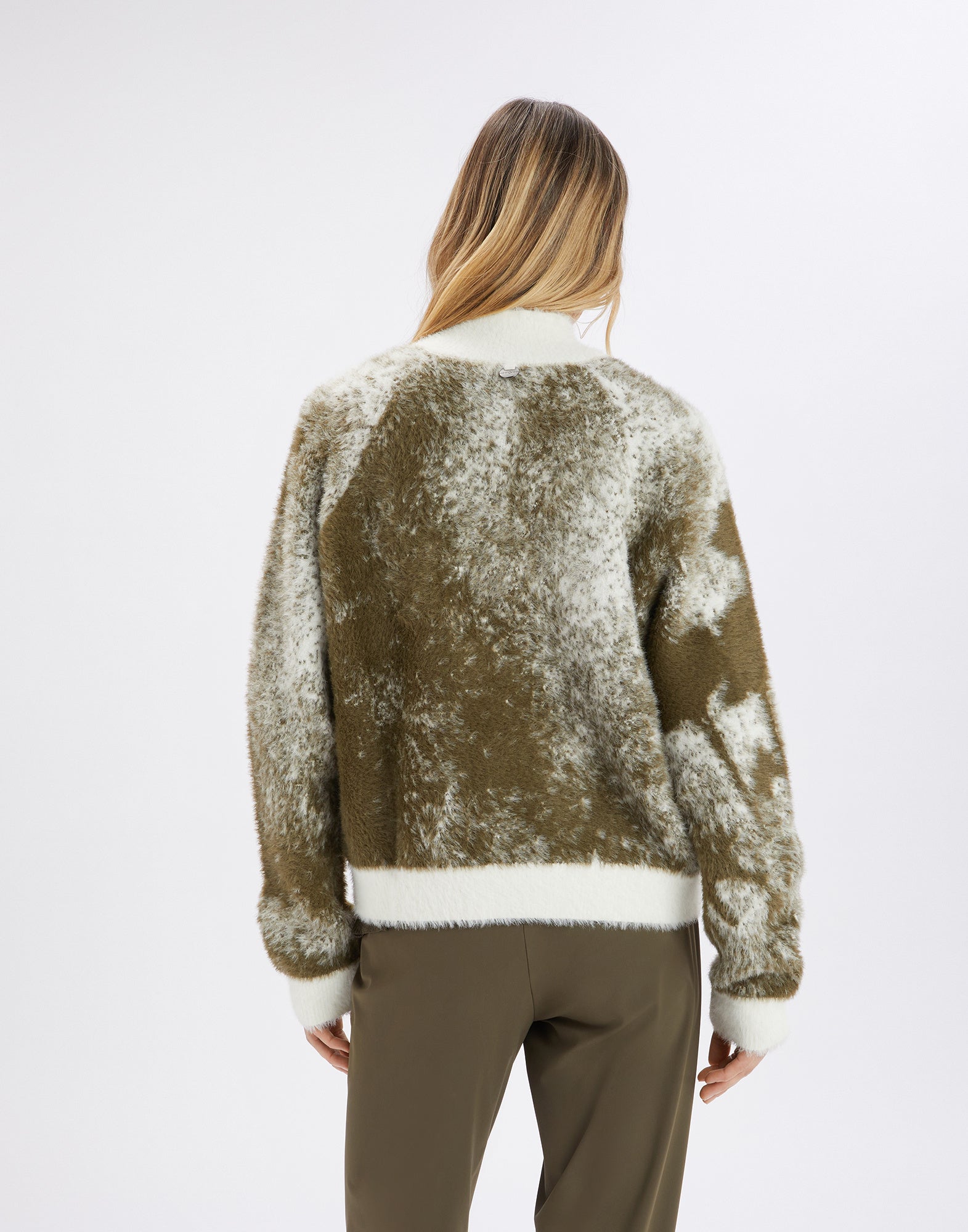 Back view of the SUMMON UP cardigan, oversized and crafted from bicolor jacquard, with white cuffs, stand collar, and floral pattern on the right sleeve.