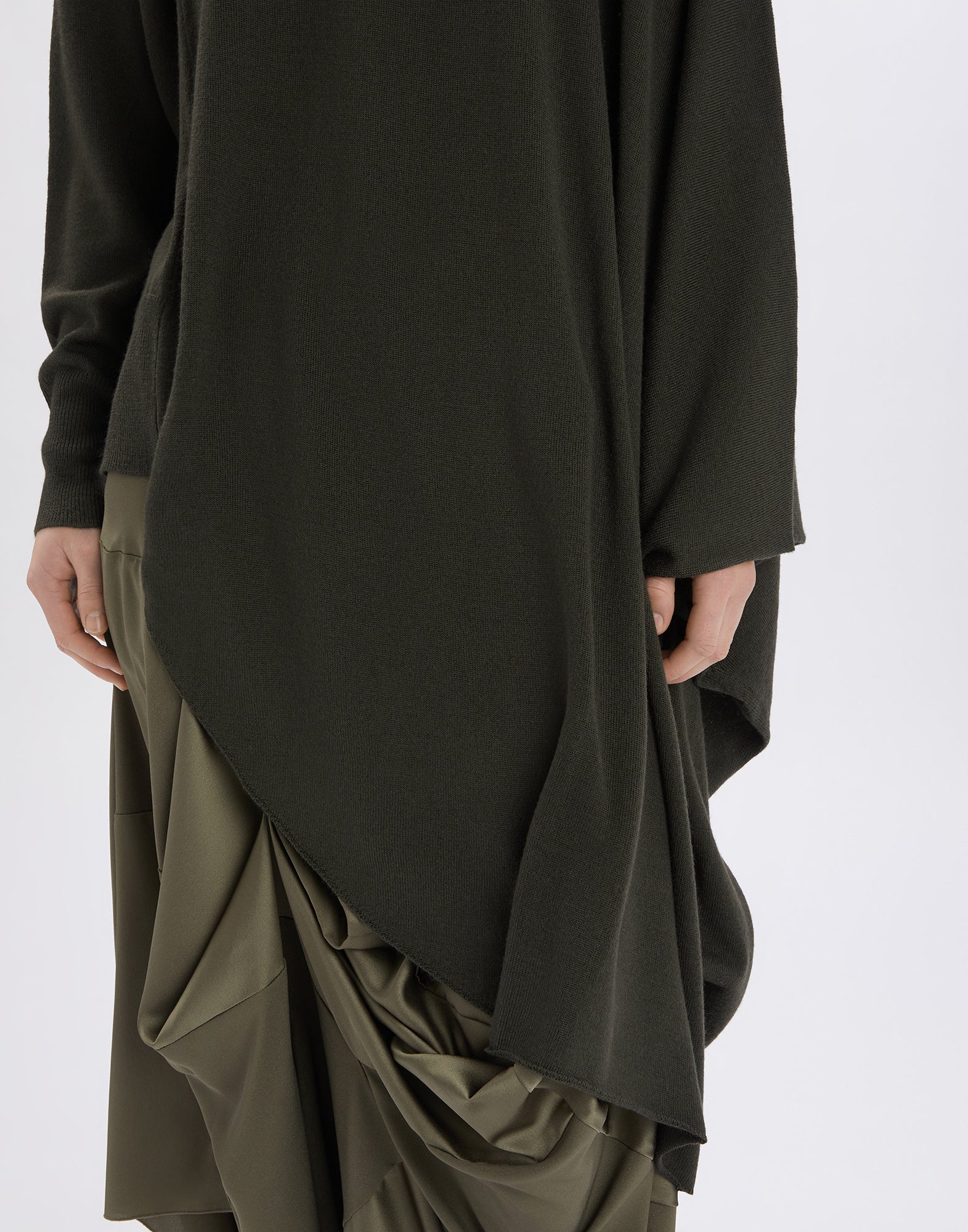Front view of the ON SET tunic featuring an asymmetrical, flowing hem in black wool blend, beginning at the right hip and falling below the left knee.