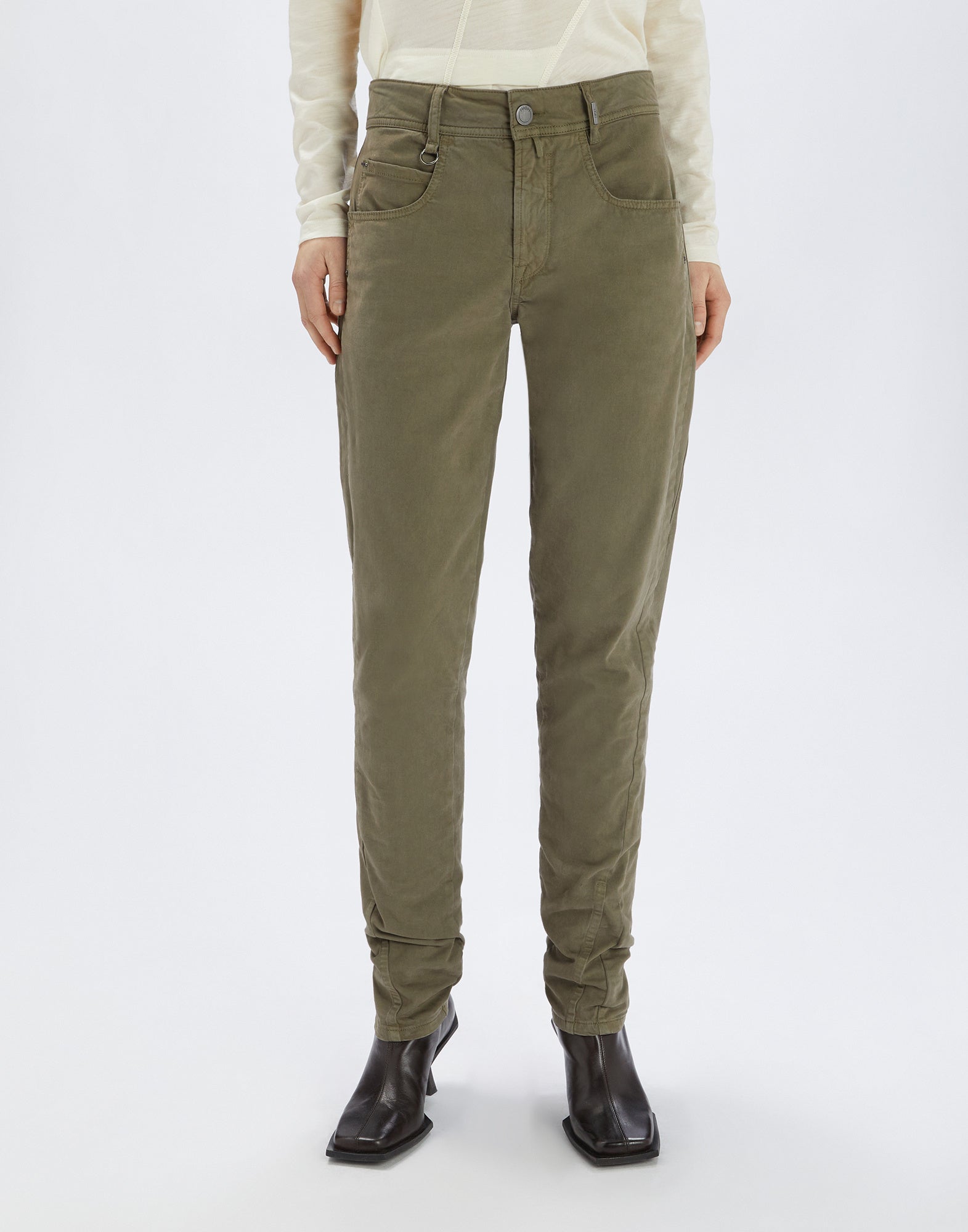Front view of the HAPPLY pants, olive green, made from stretch cotton with visible seams, side and back pockets, worn by a person with black boots.