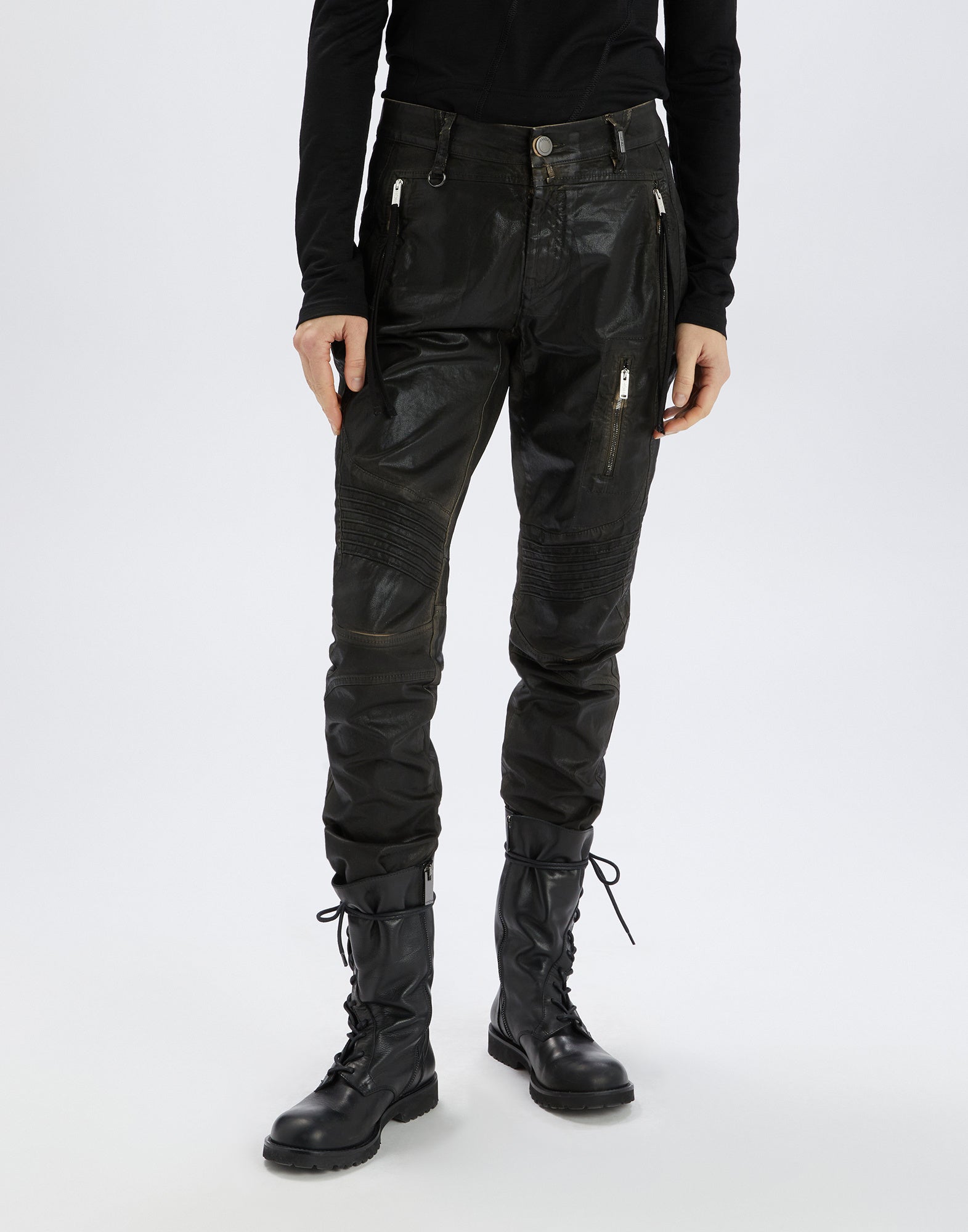 Frontalansicht einer Person, die die INKLING Jeans trägt. Die Jeans hat einen lederähnlichen Effekt, sichtbare Reißverschlüsse an den Taschen und gesteppte Kniepartien.