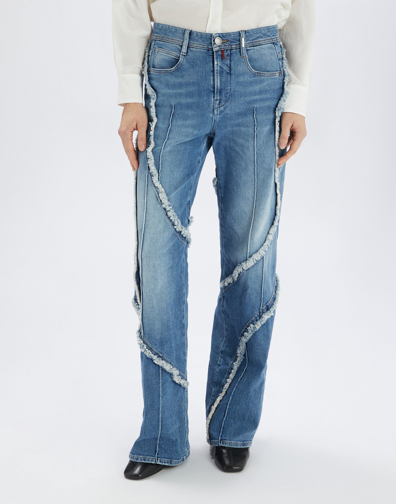 Frontalansicht der INDULGE Jeans mit weitem Bein, offenen, ausgefransten Kanten, sichtbaren Nähten und mittlerem Bund in hellem Jeansblau, getragen von einer Person.