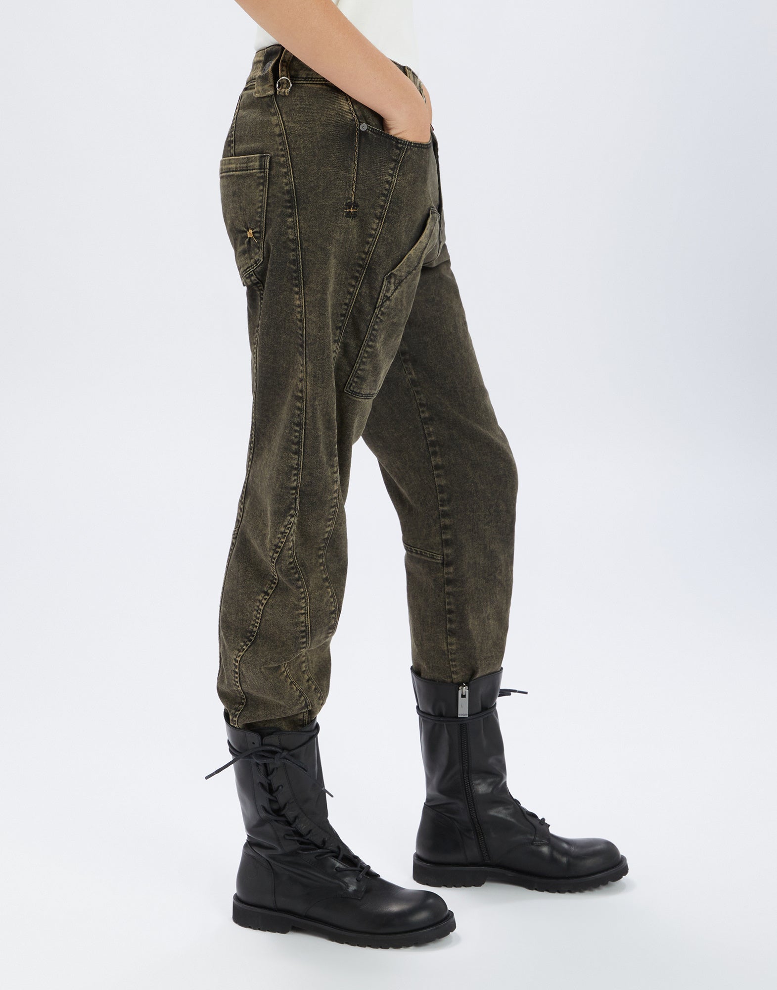 Seitenansicht der WIDE LEG SADDLE Jeans in dunkler Used-Optik mit markanten Nähten und mehreren Taschen, getragen mit schwarzen Schnürstiefeln.