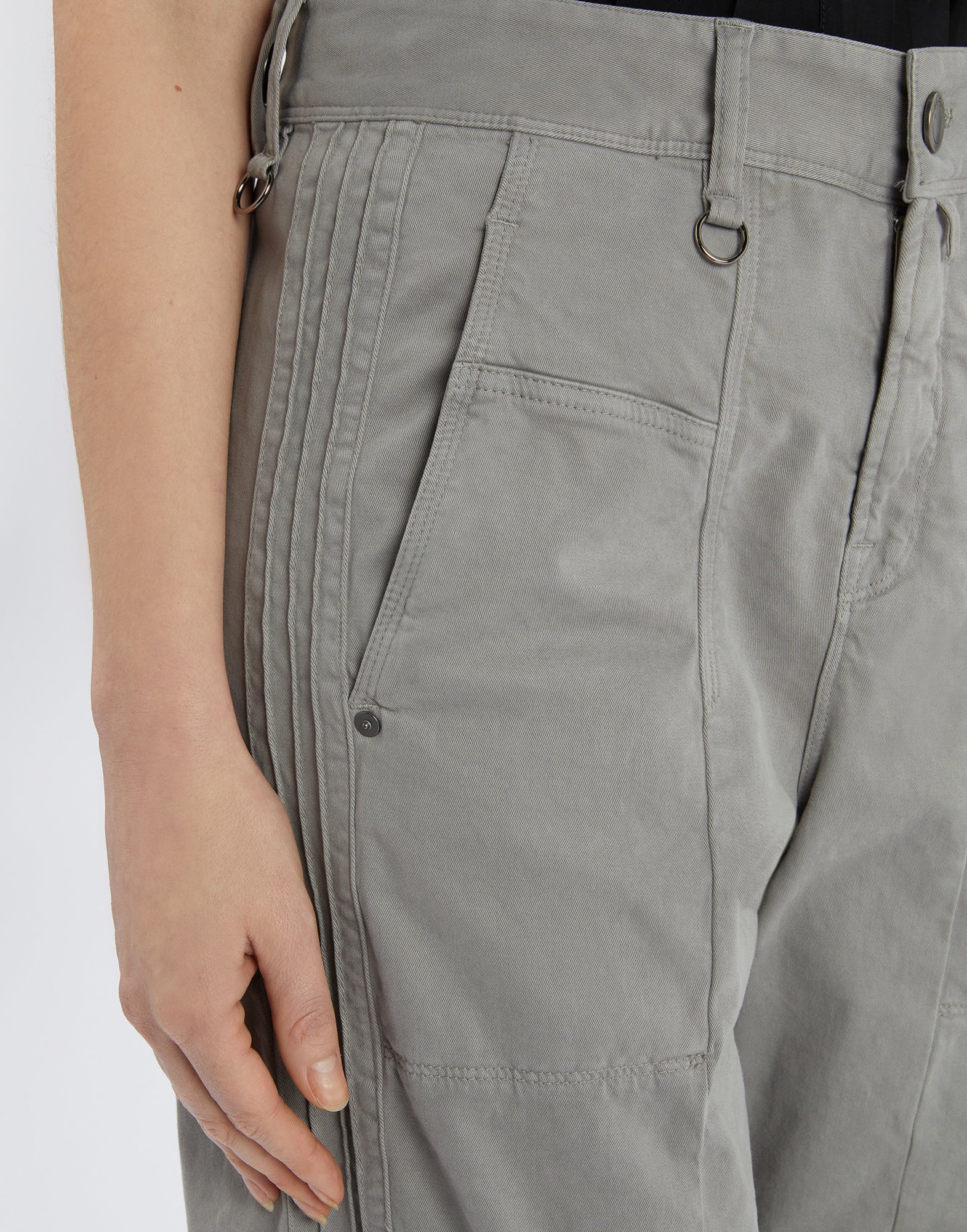 Detailansicht aus seitlichem Winkel: ACTIVATE Hose mit sichtbaren flachen Nähten, Gürtelschlaufen samt Metallschlaufe, Frontknopf und seitlicher Tasche.