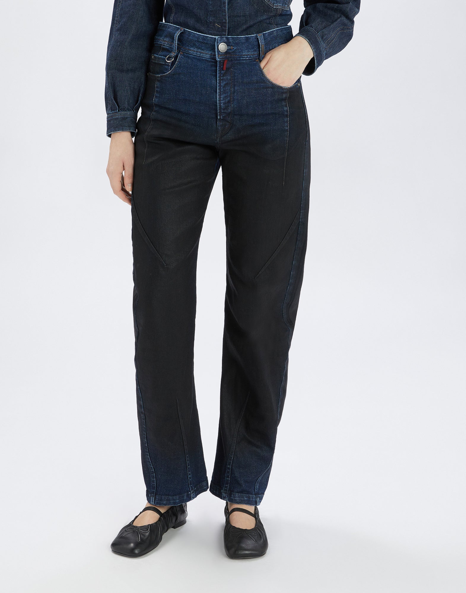 Frontalansicht: Eine Person trägt die TRICE Jeans, gerade geschnitten mit gebogener Banana-Beinform, sichtbare Nähte, zweifarbiger Denim-Look und Knie-Falten.